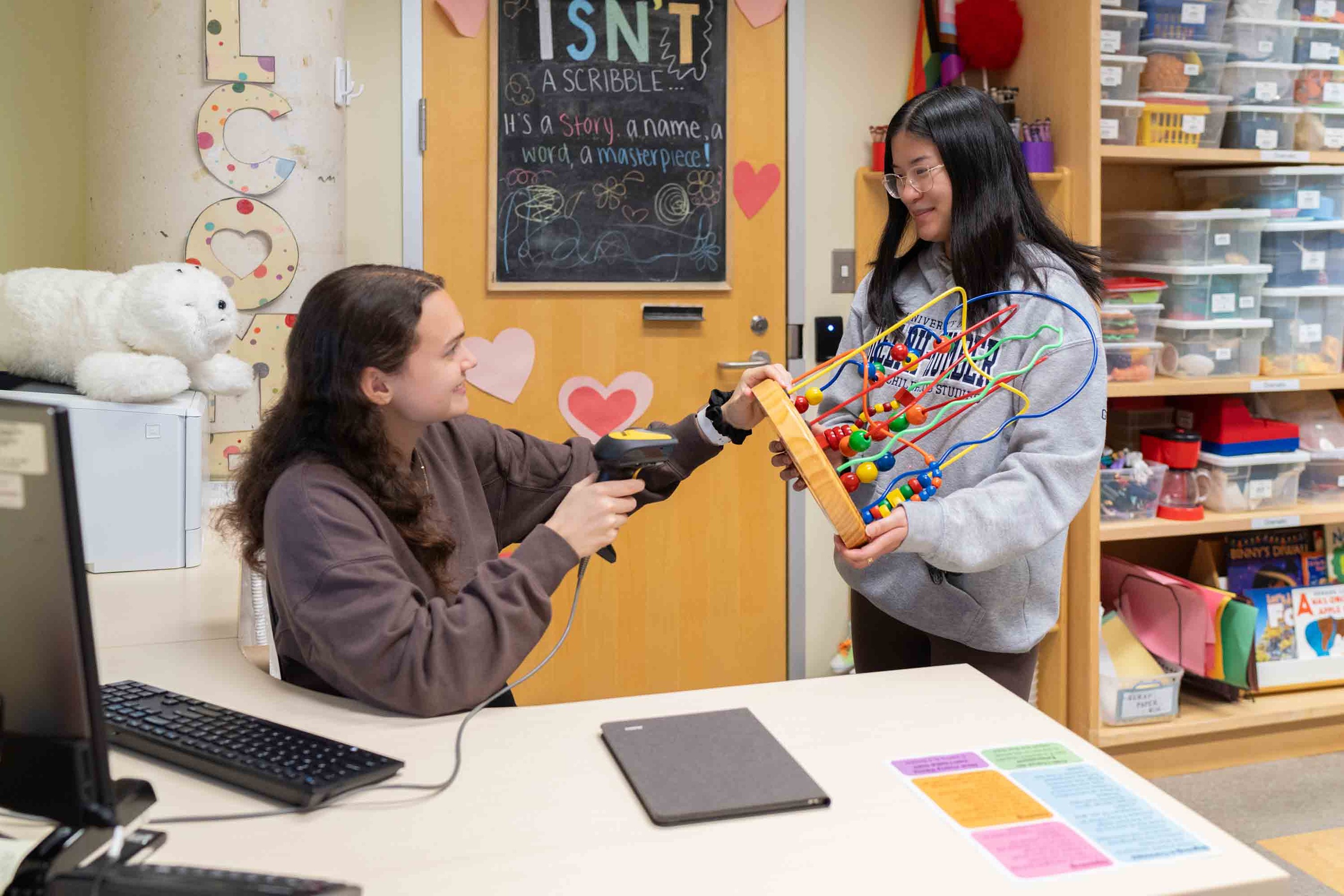 Students in a colourful room, with one scanning a toy at a computer