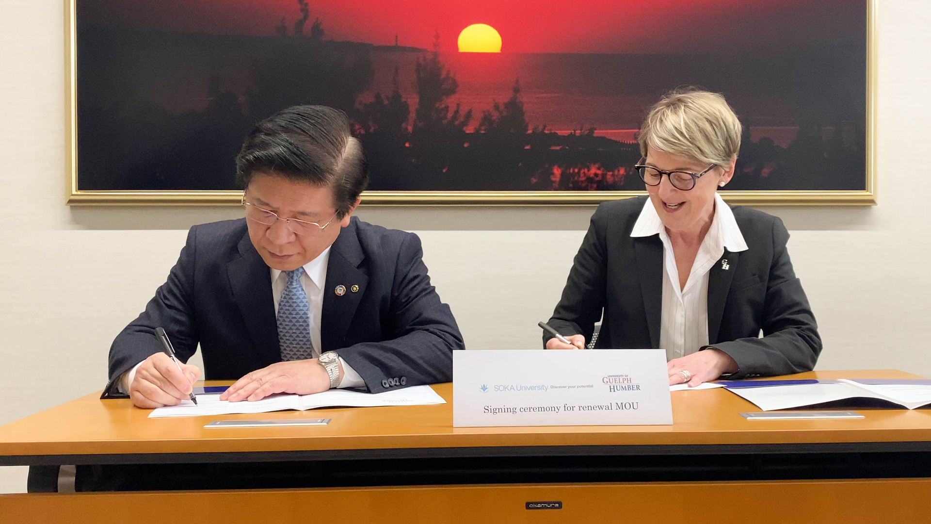 Two individuals signing their respective papers 