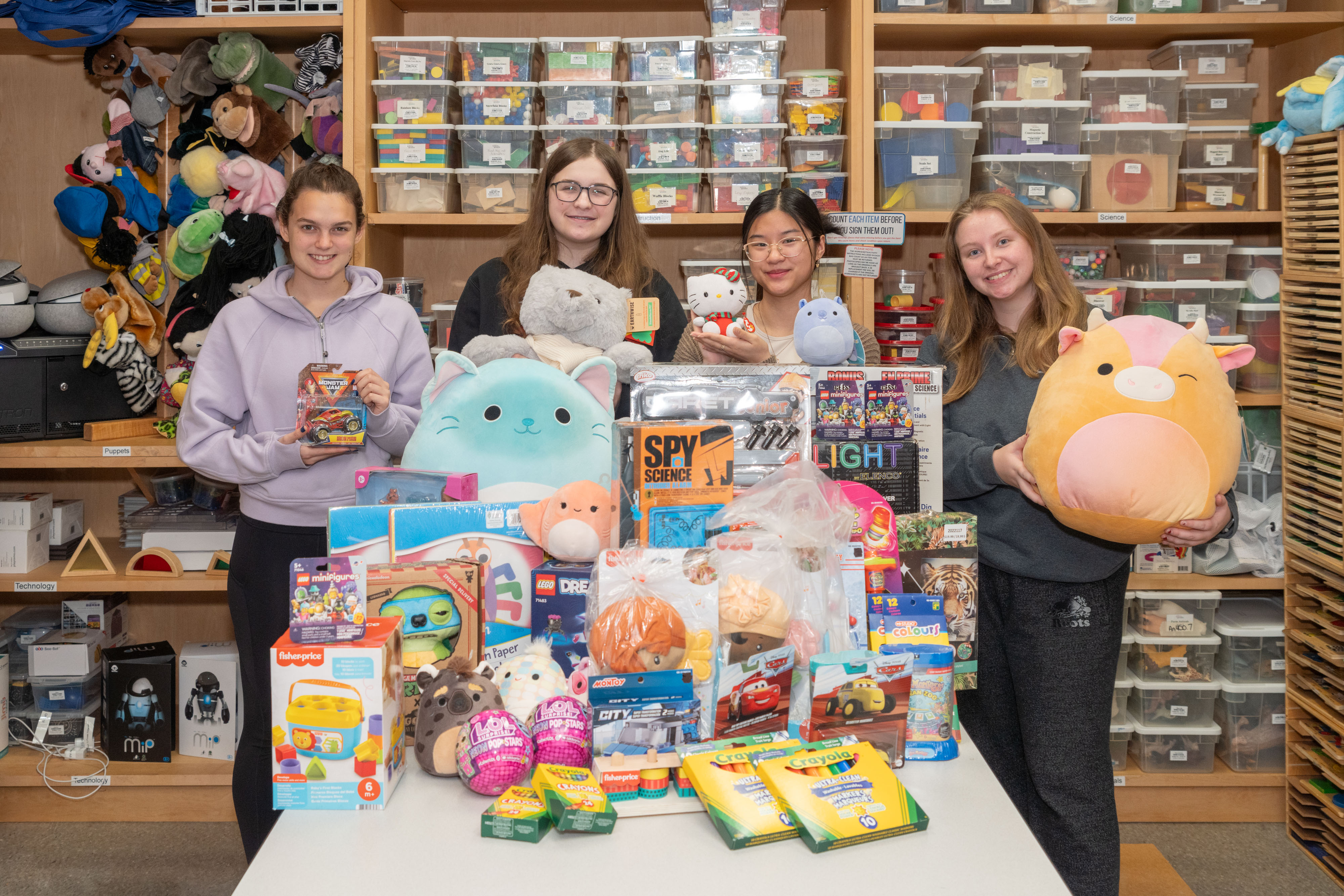 A group of four students pose with a pile of colourful toy donations