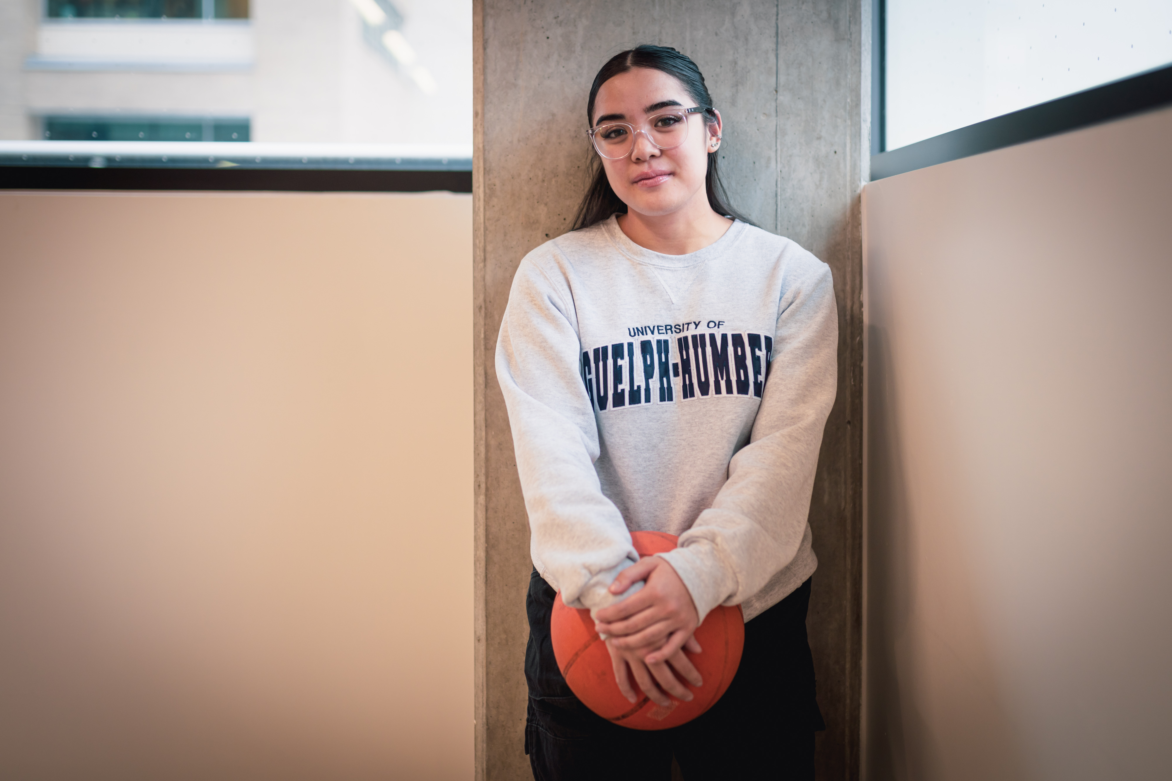 Hope leans against a wall holding a basketball