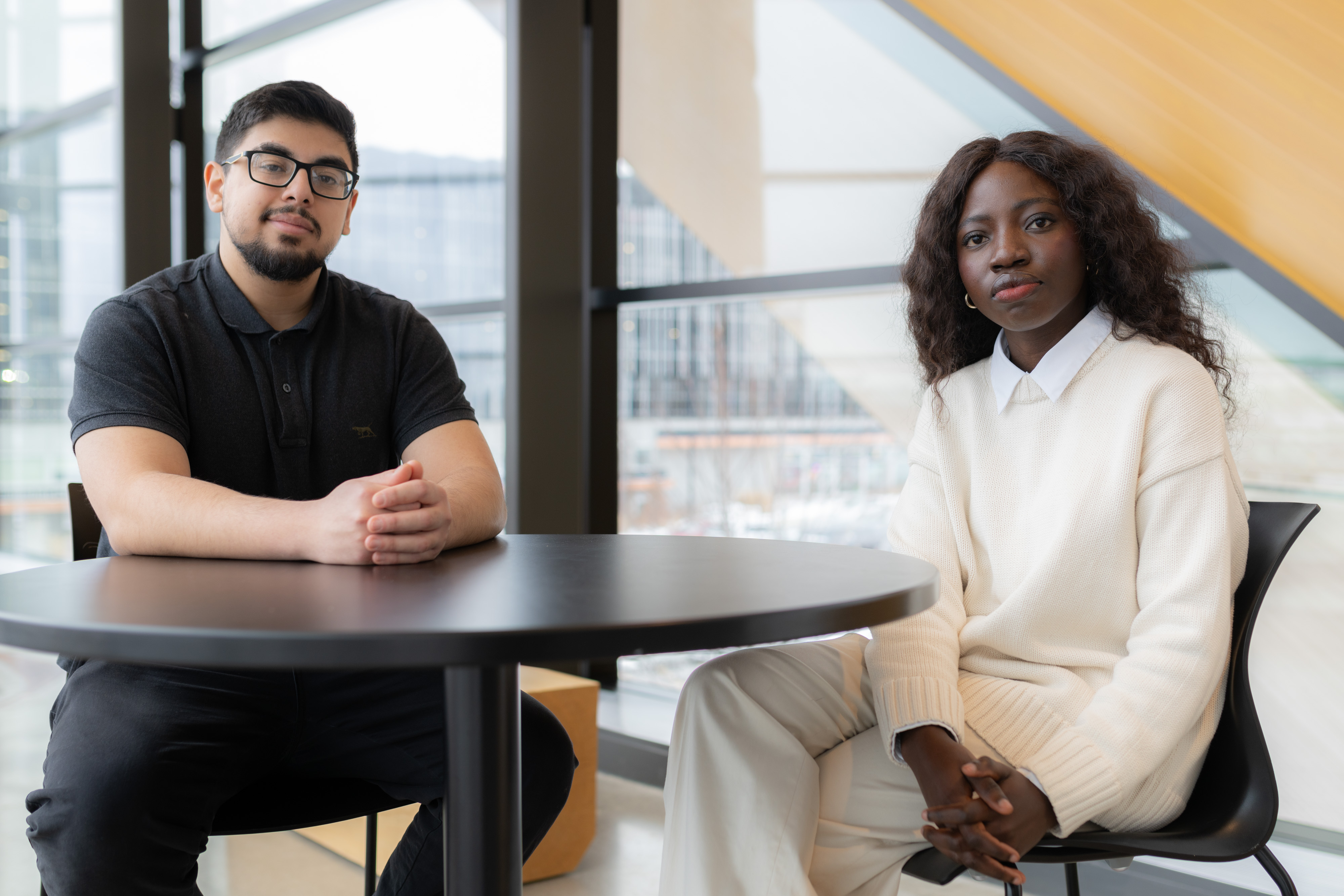 Two students sit together at a table looking ahead