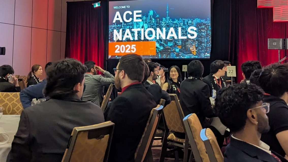 A group of people sit at tables with a sign in the background that says welcome to ACE Nationals 2025