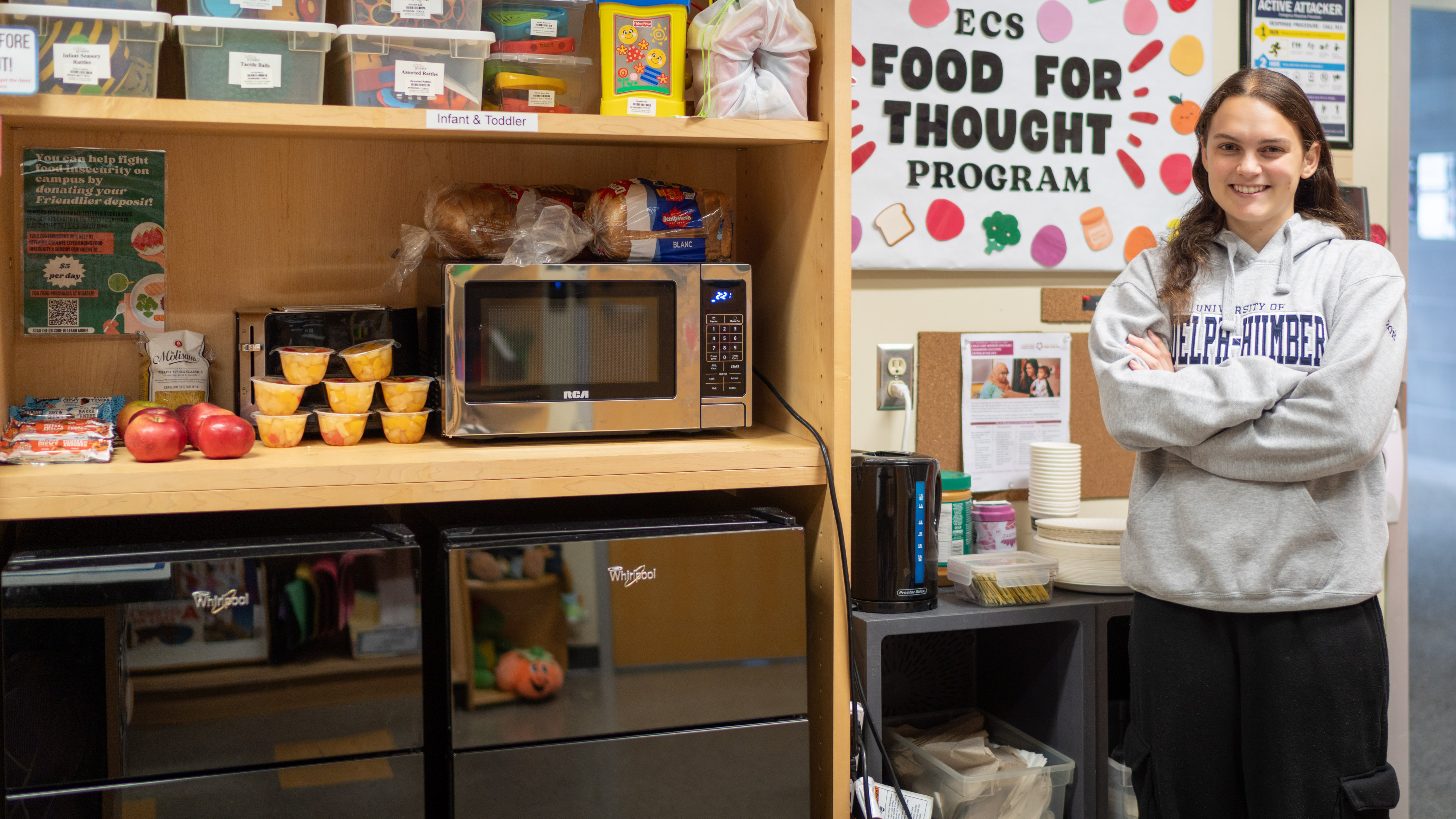 A student posing with a snack pantry part of the Food for Thought program