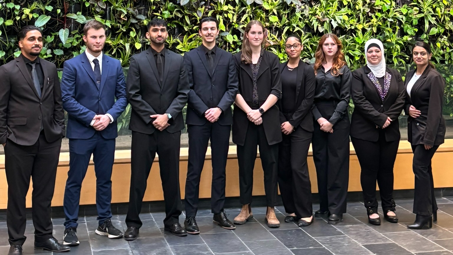 A group of nine Guelph-Humber student participants pose in front of plant wall