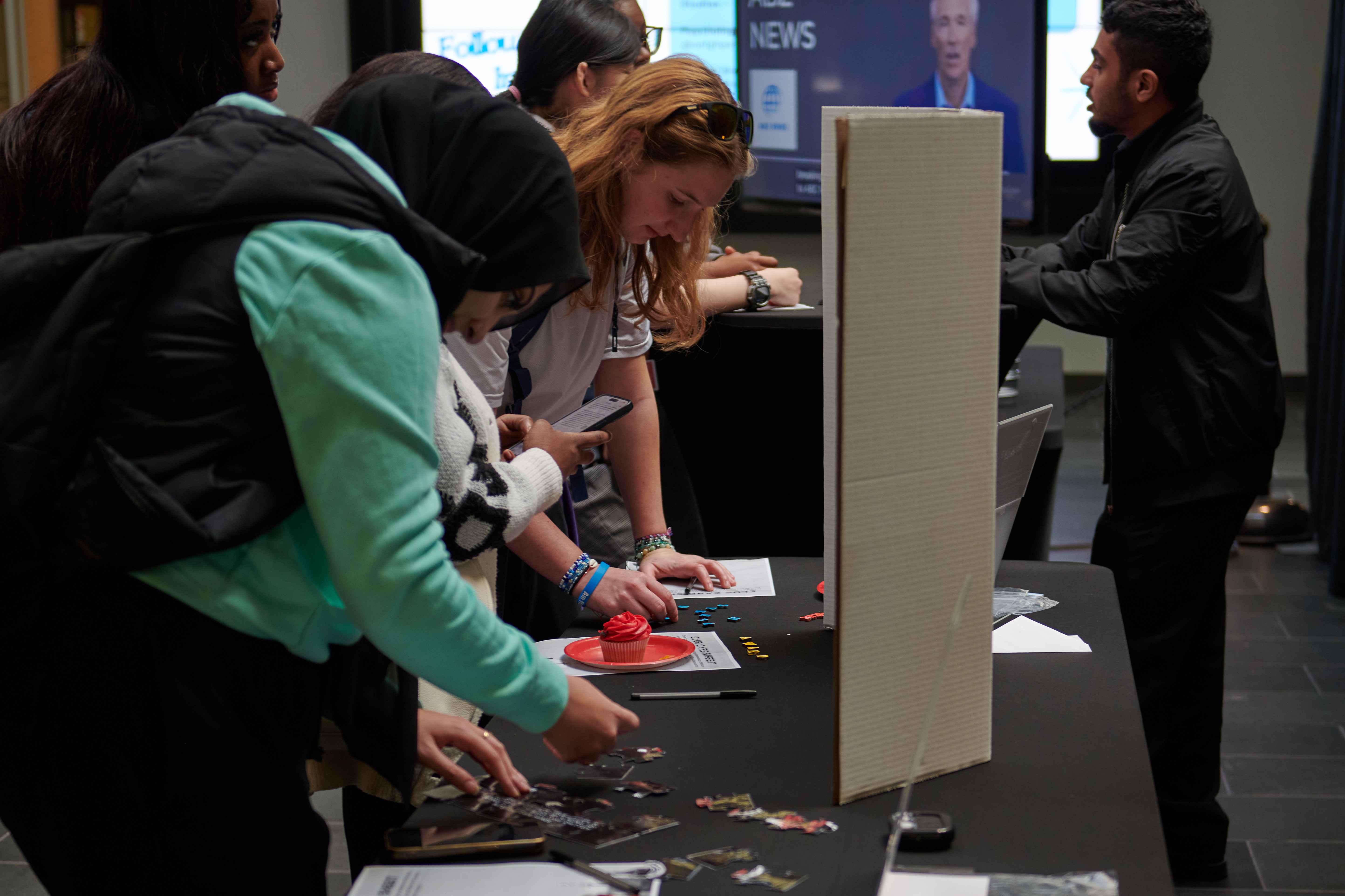 A group of students congregating at a table to complete puzzles