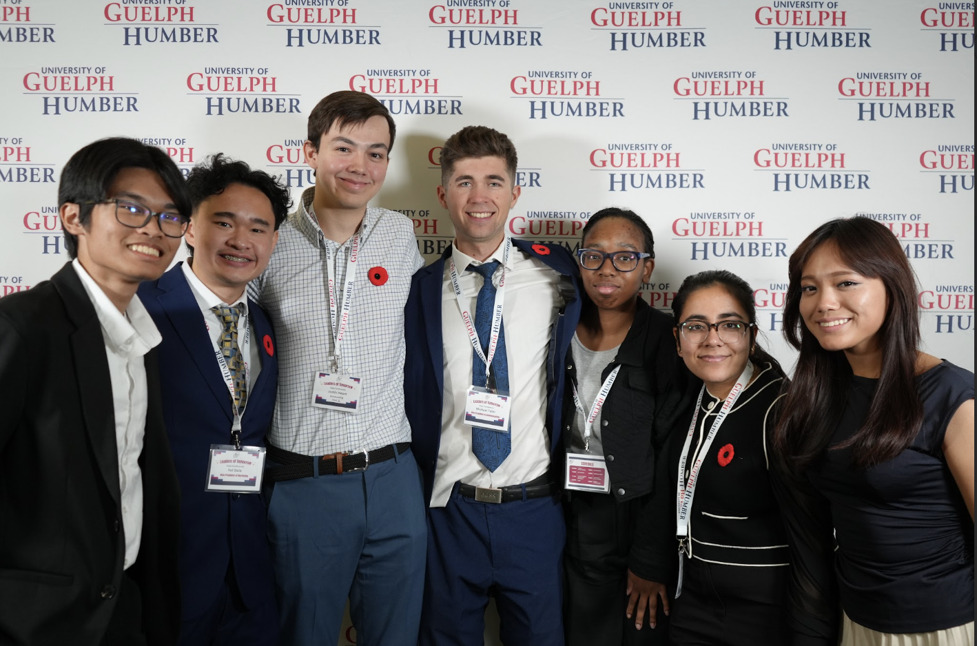 A group of seven students pose in front of a Guelph-Humber banner