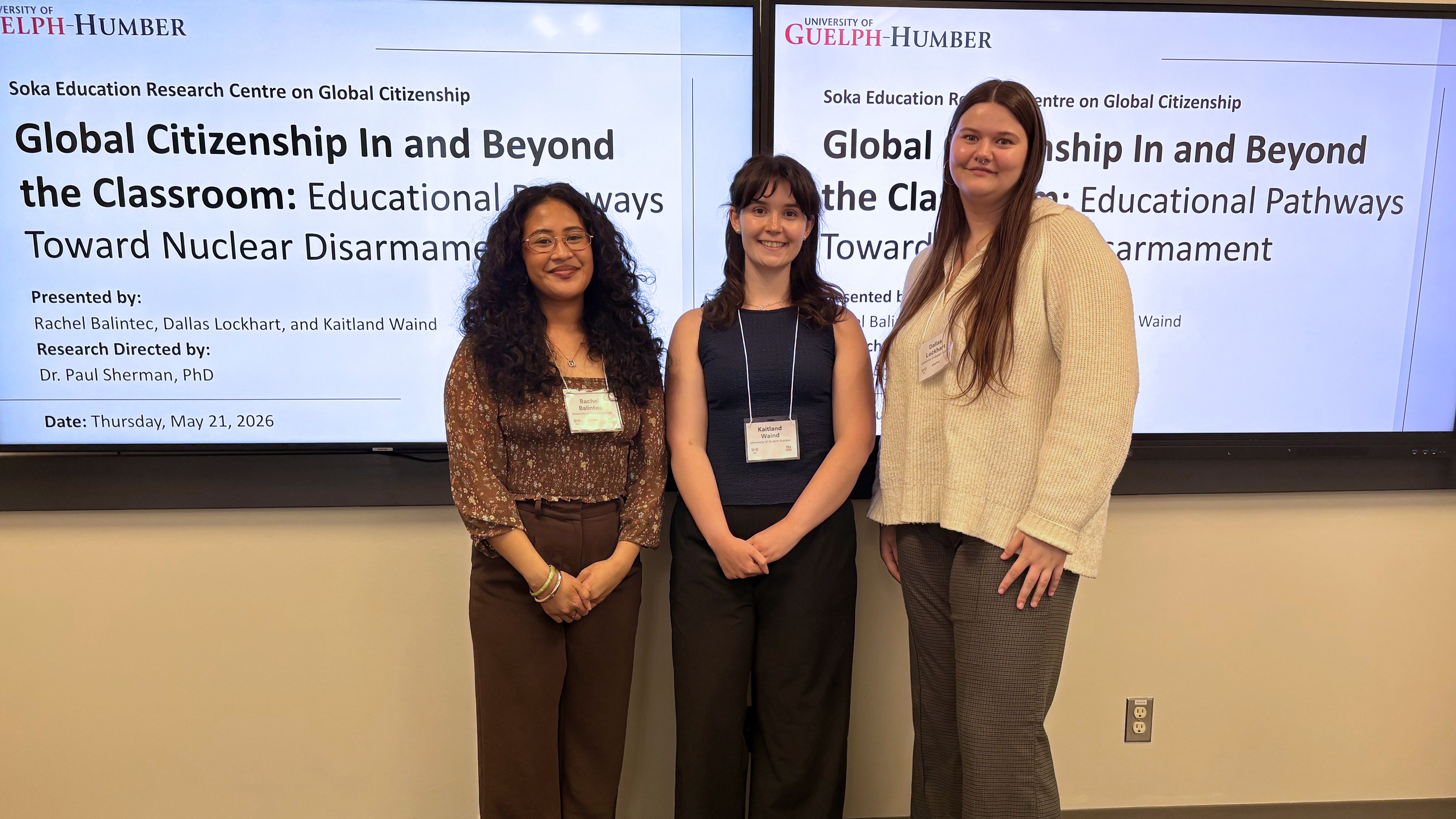 Three students stand in front of their research projected onto a screen
