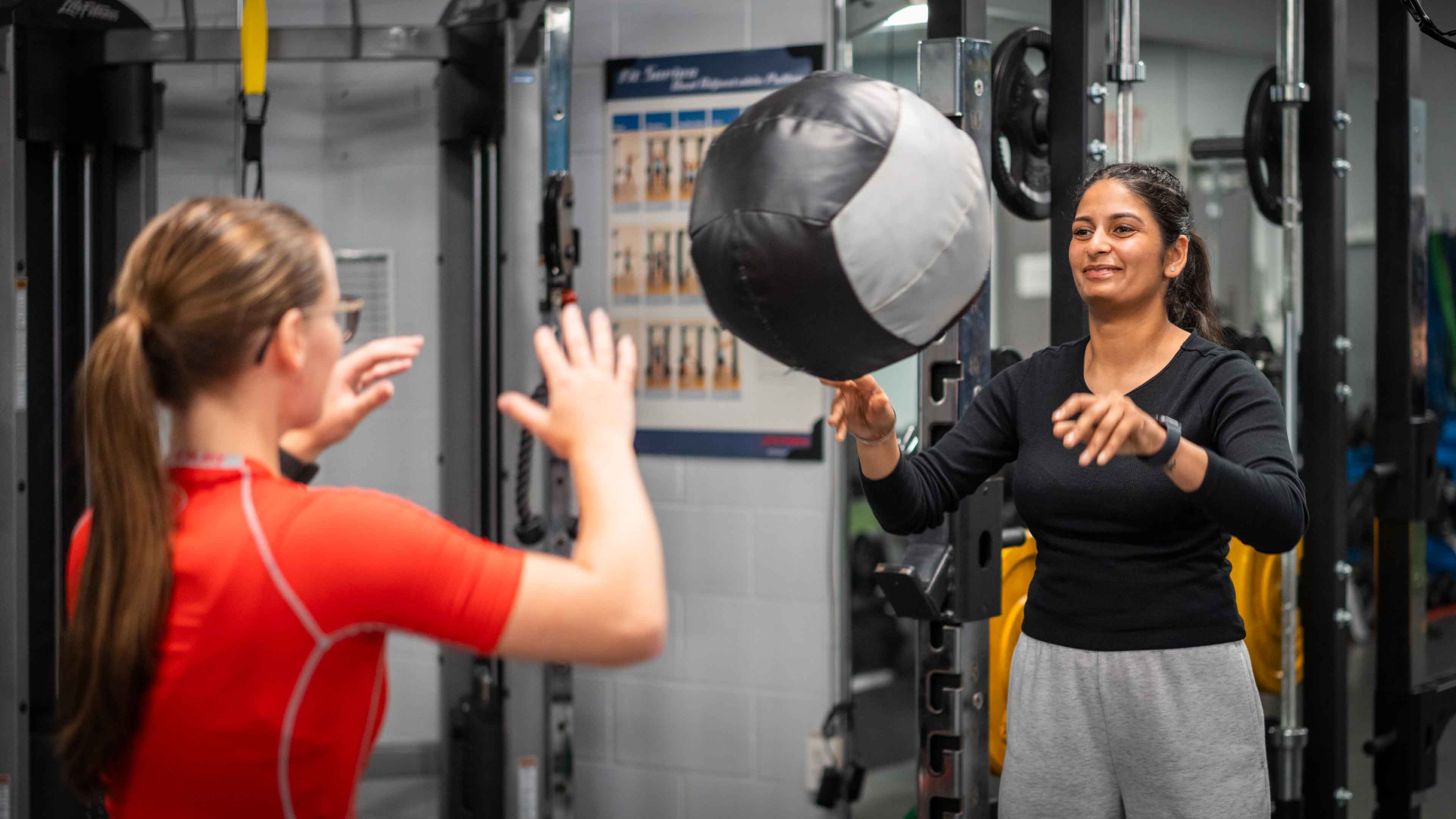 Someone throwing a ball at another person in a gym