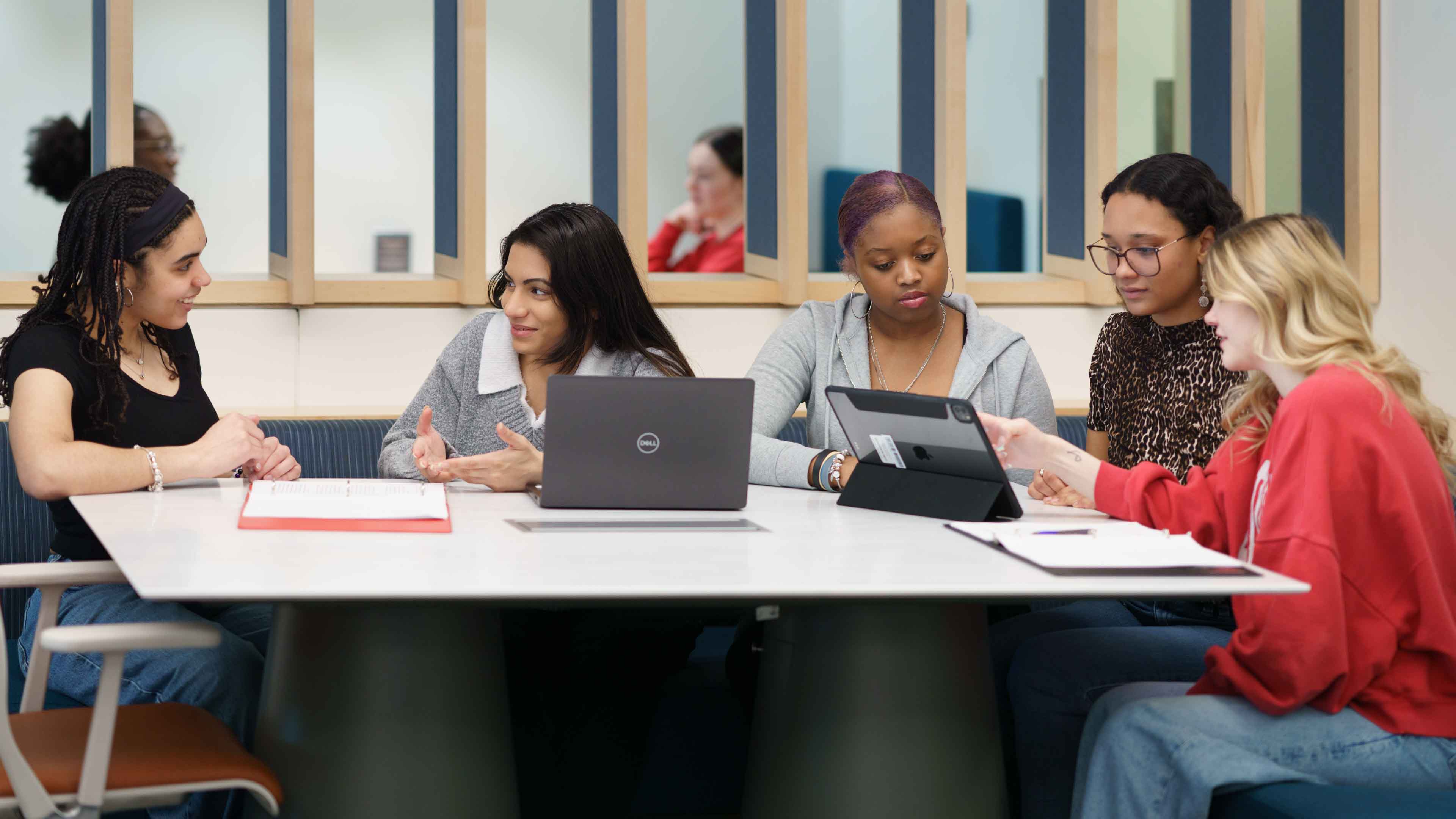 Students sit around at a table with laptops