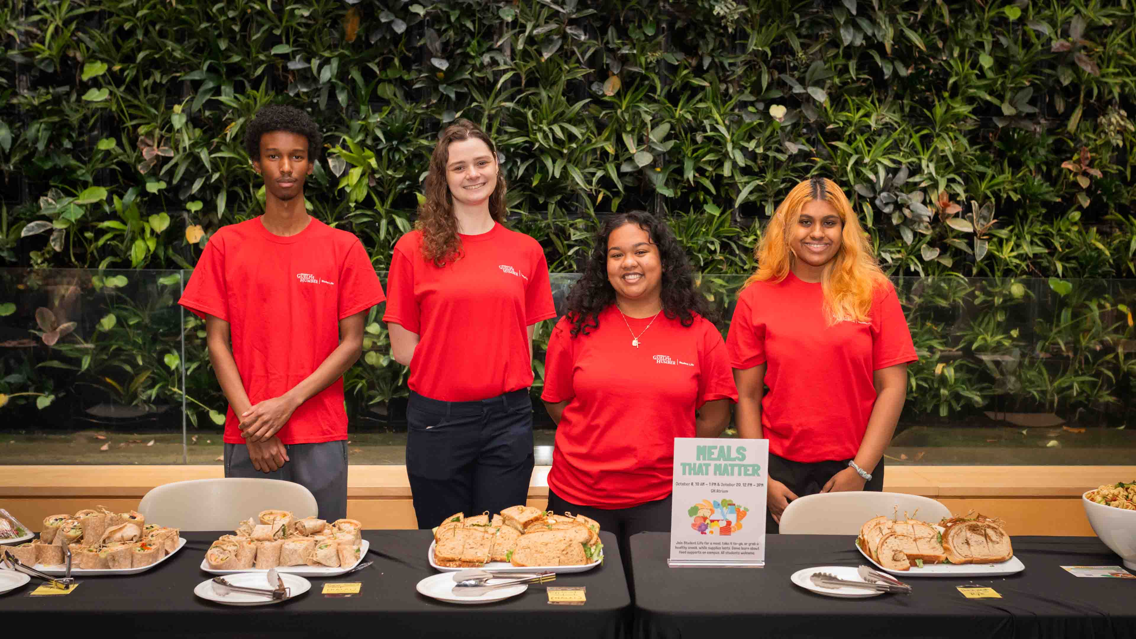 Four students in red shirts pose with food during Meals That Matter