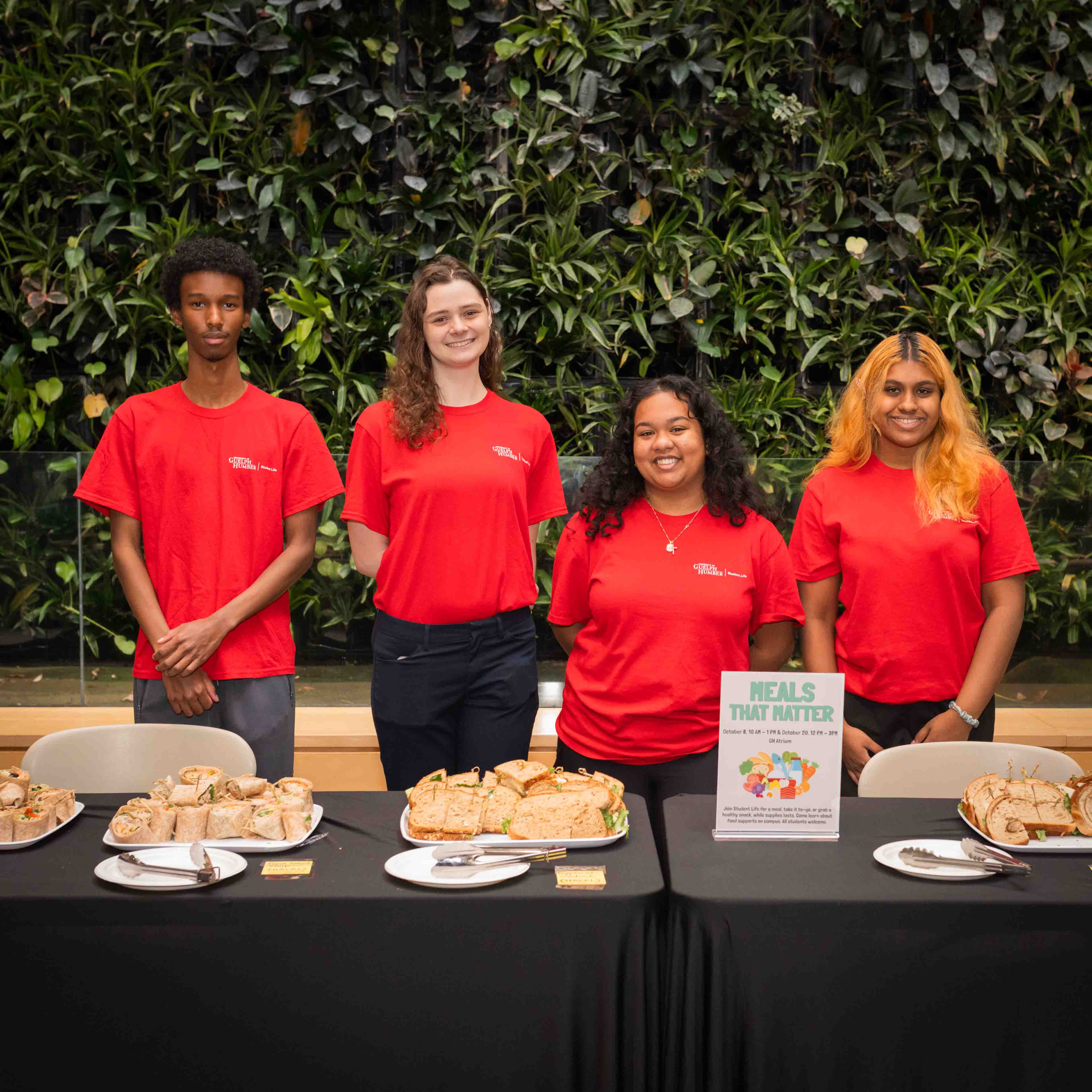 Four students in red shirts pose with food during Meals That Matter