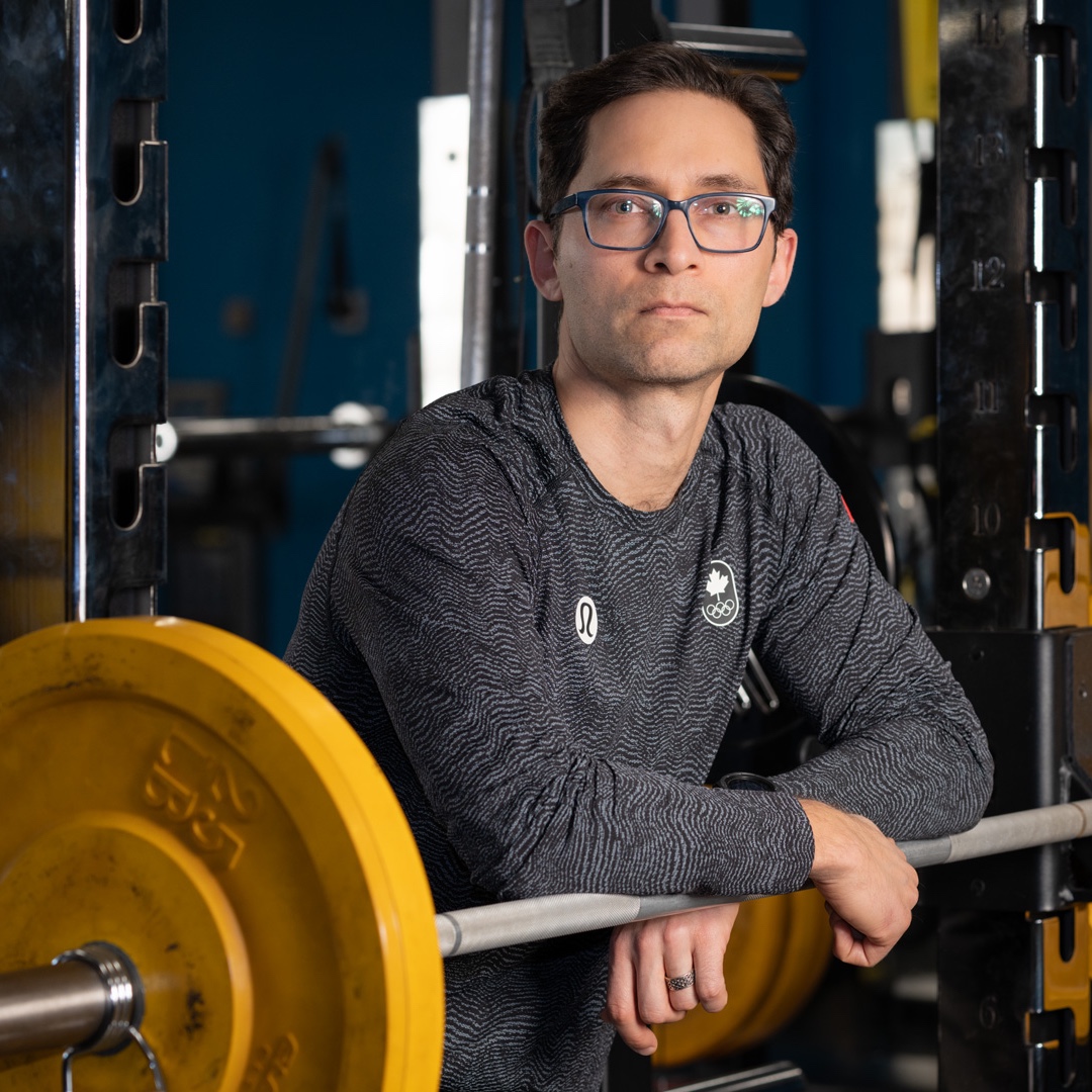 Darian Silk leaning forward on a bar at a squat rack