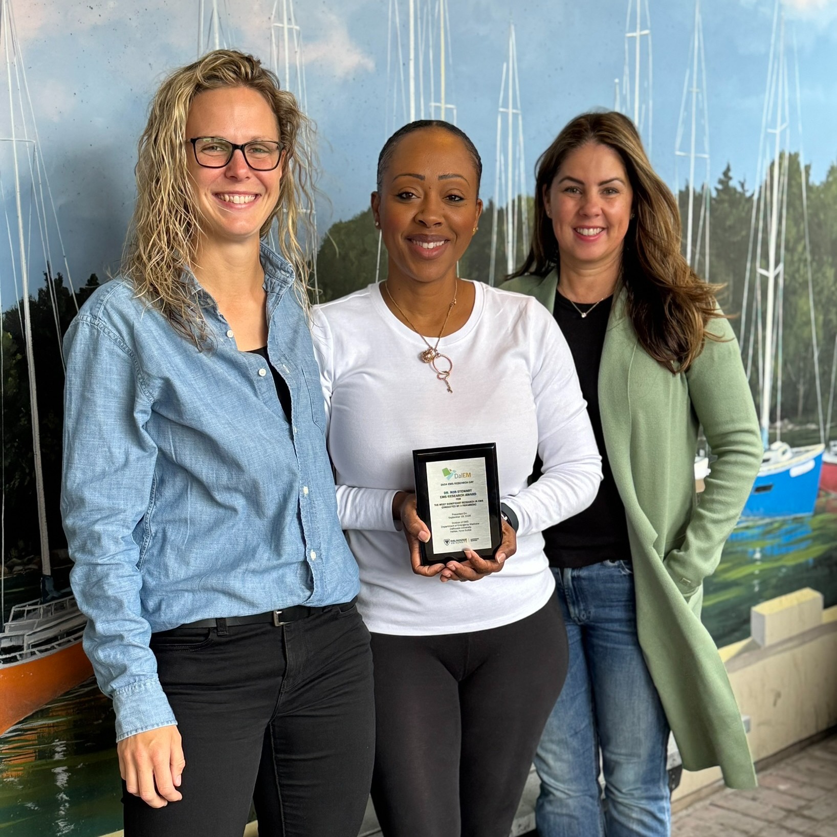 Three people posing with an award plaque