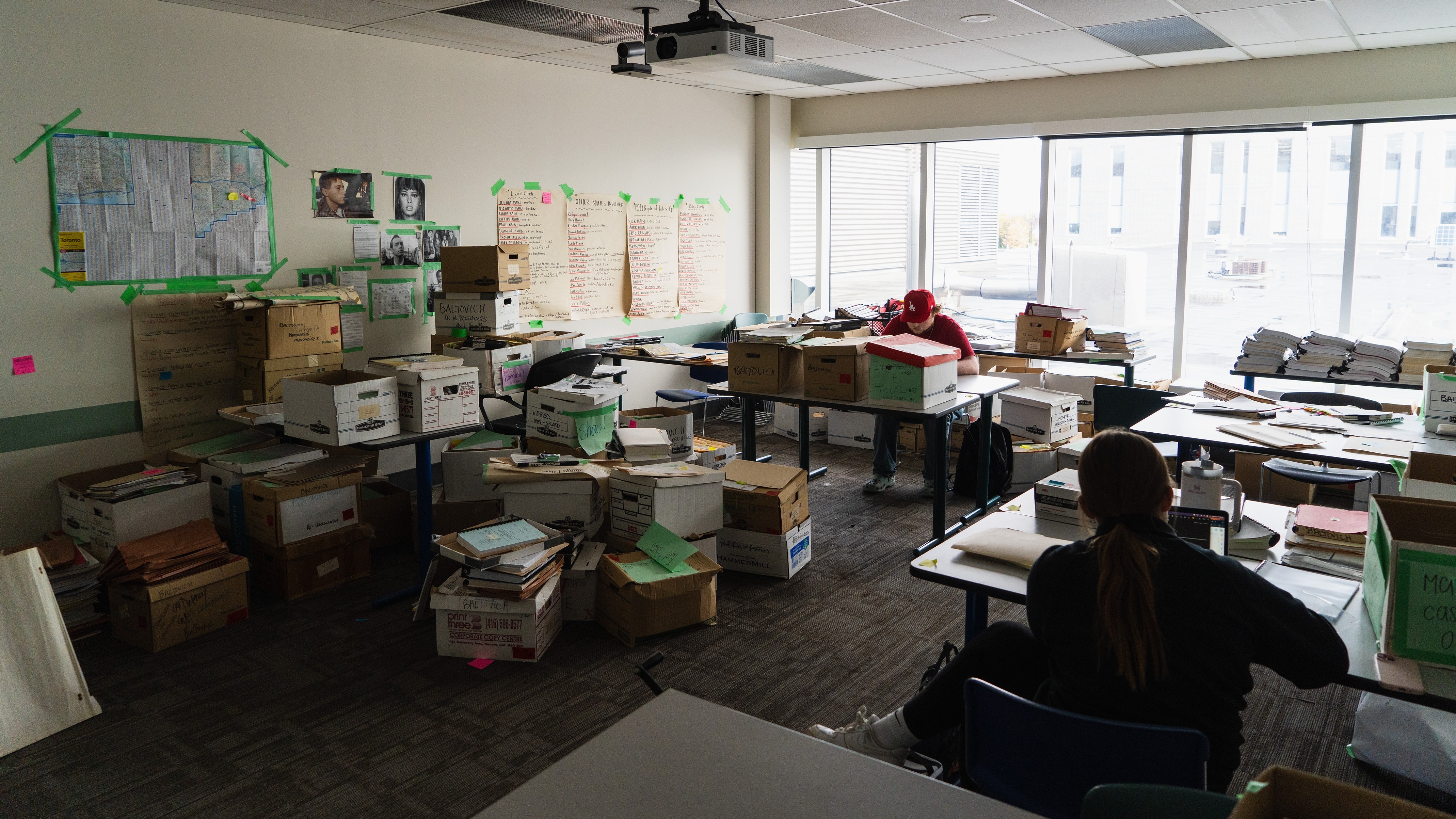 Room filled with boxes and files, with two students reviewing documents