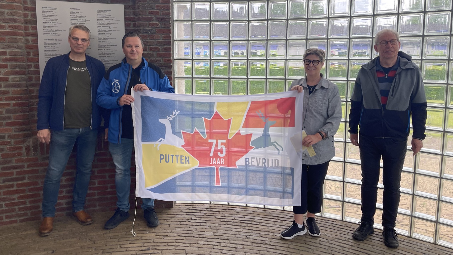 Four people holding commemorative flag by a window