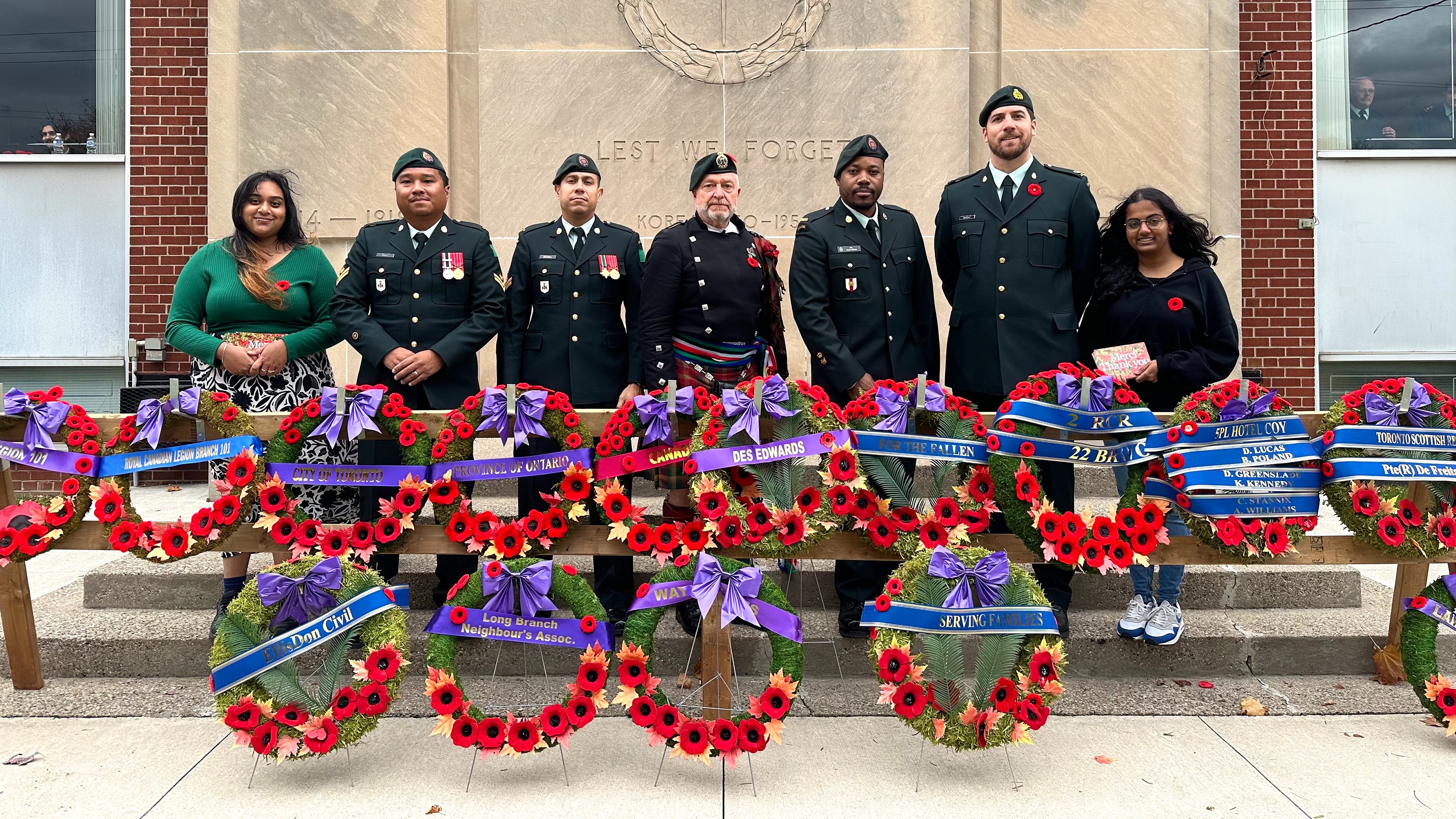 Students and veterans posing in front of wreaths