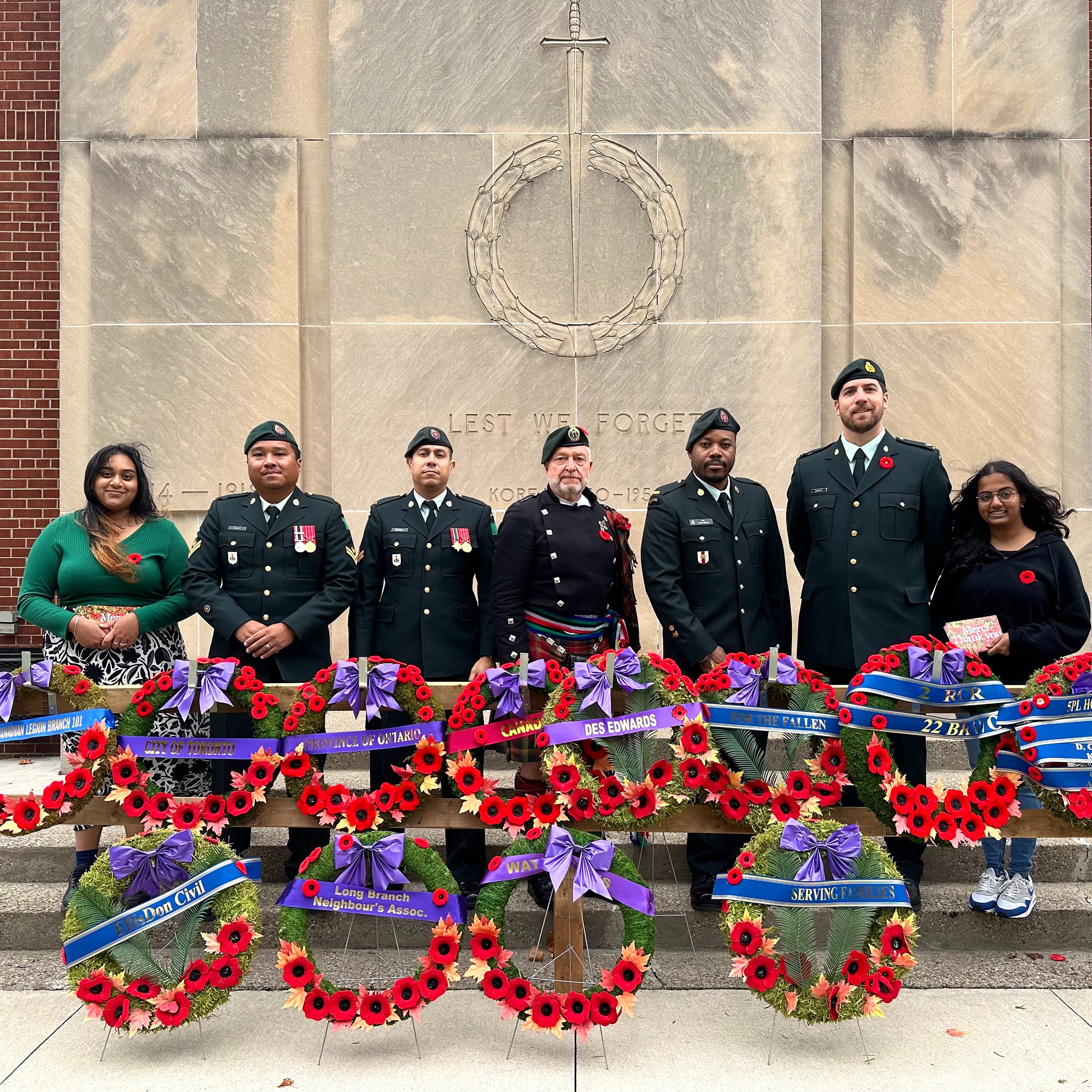 Students and veterans posing in front of wreaths