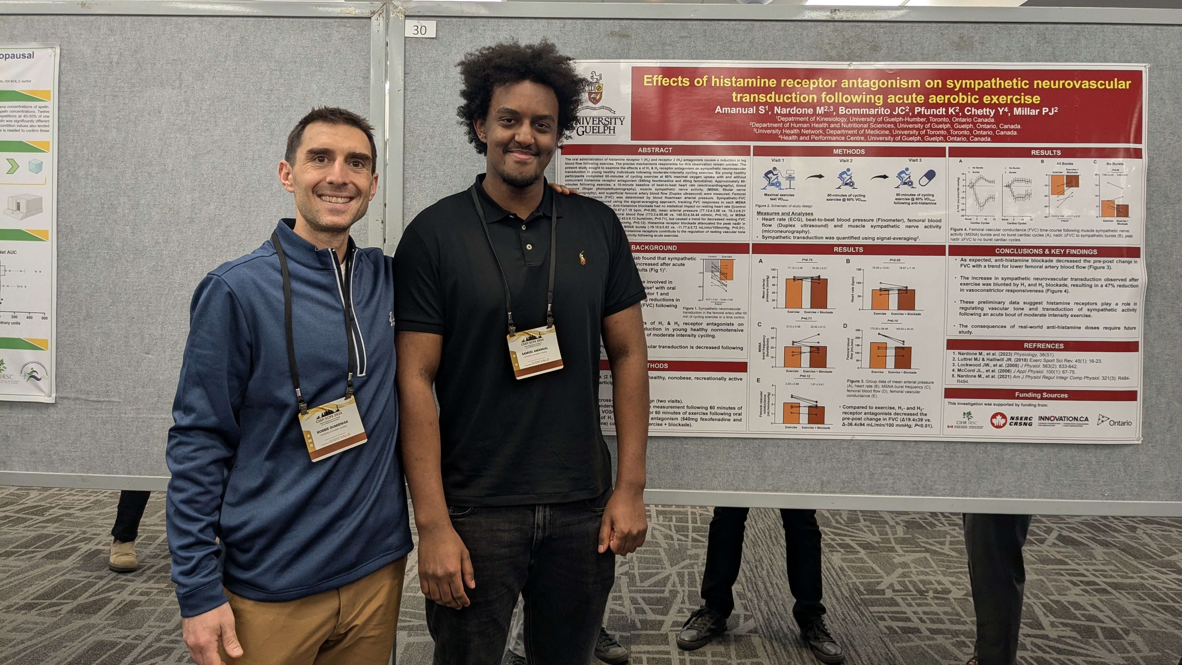 Two people pose in front of a research poster board