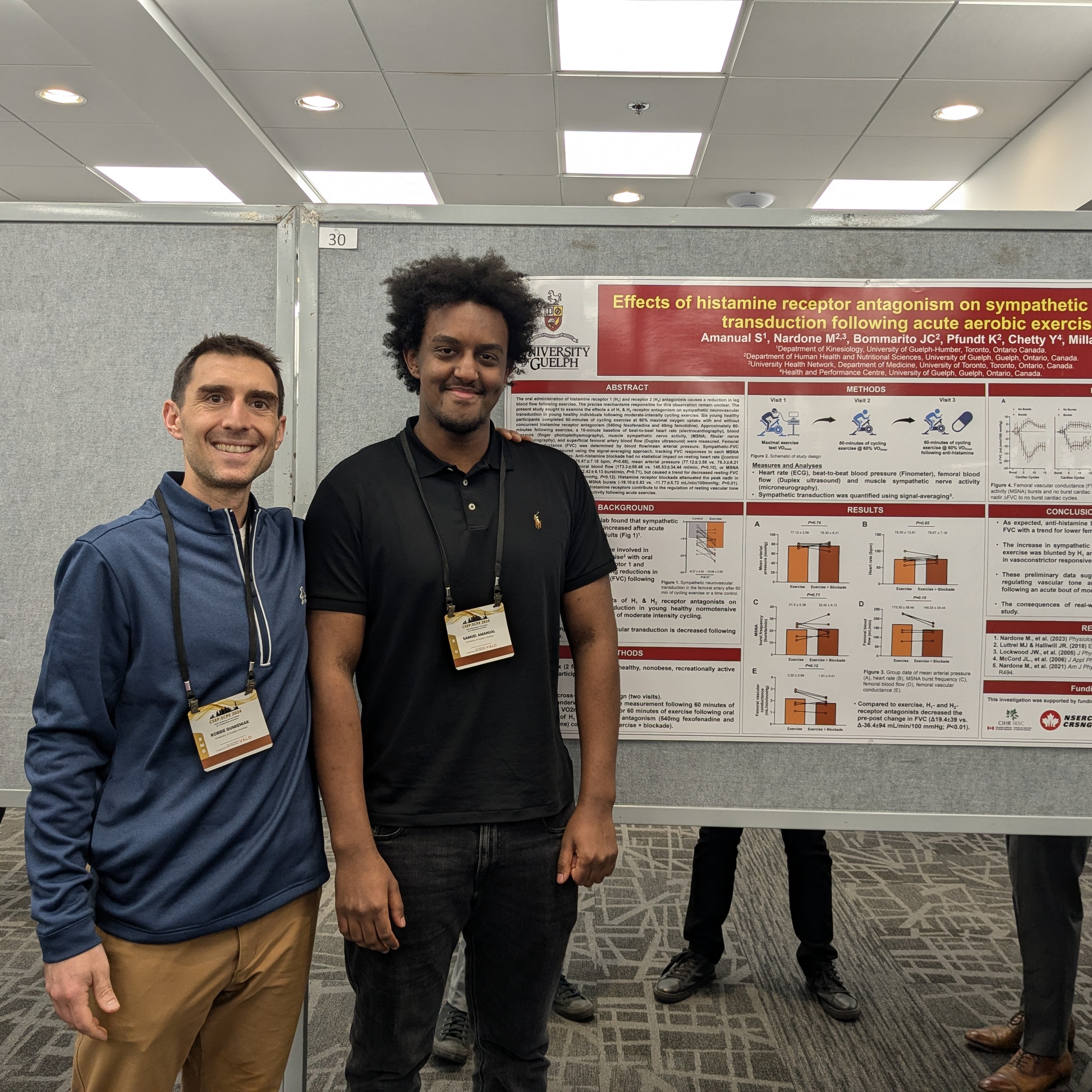 Two people pose in front of a research poster board