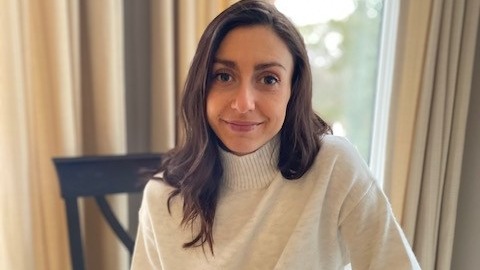 Olivia Boukydis poses for a photo sitting on a chair wearing a turtleneck sweater