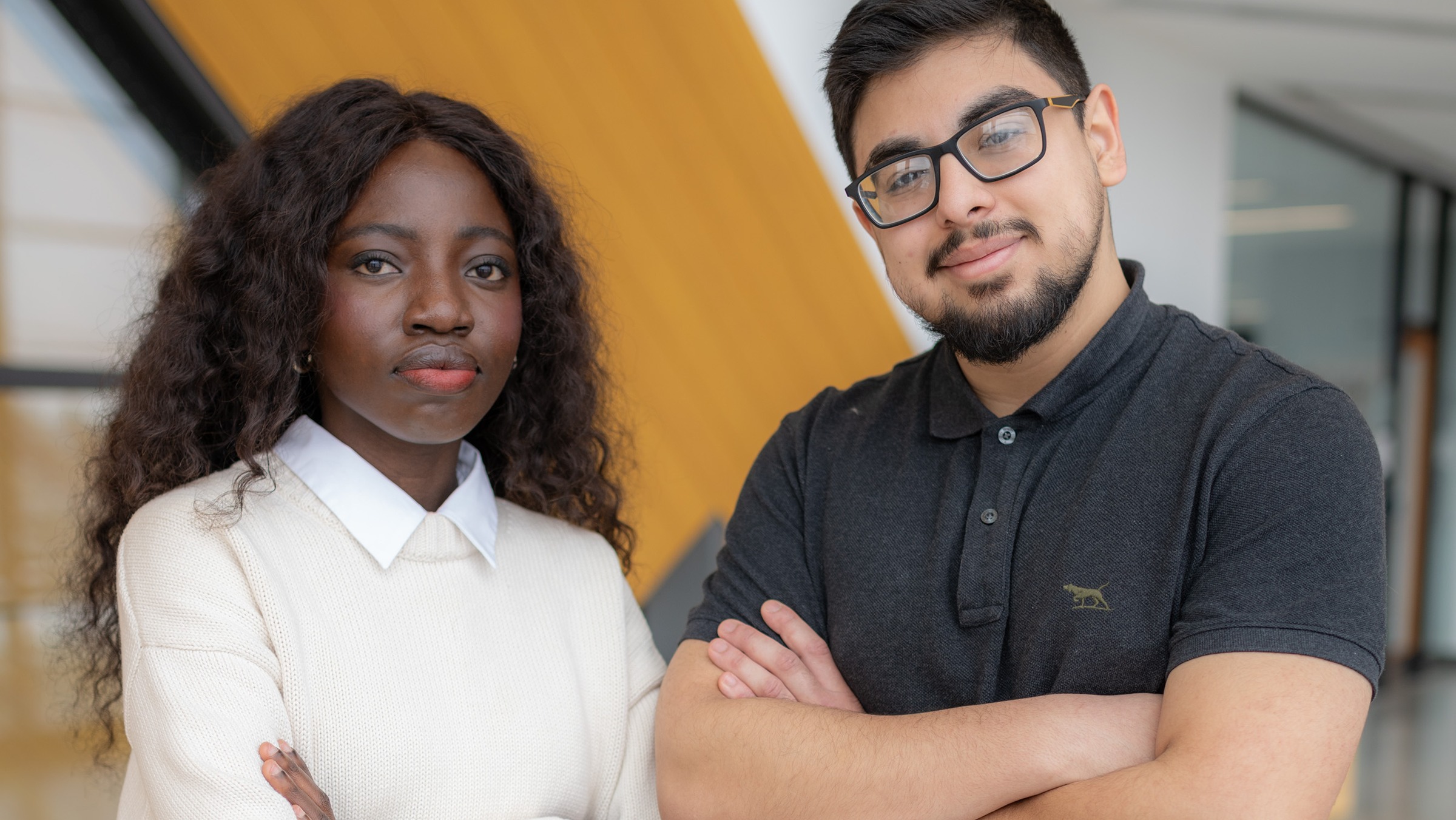 Two students pose together with their arms crossed in front of their chest