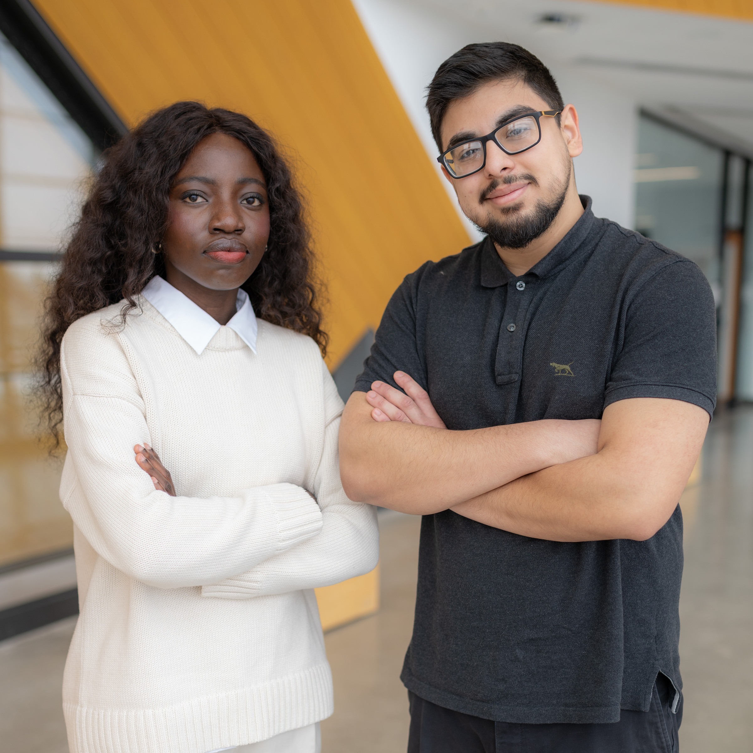 Two students pose together with their arms crossed in front of their chest