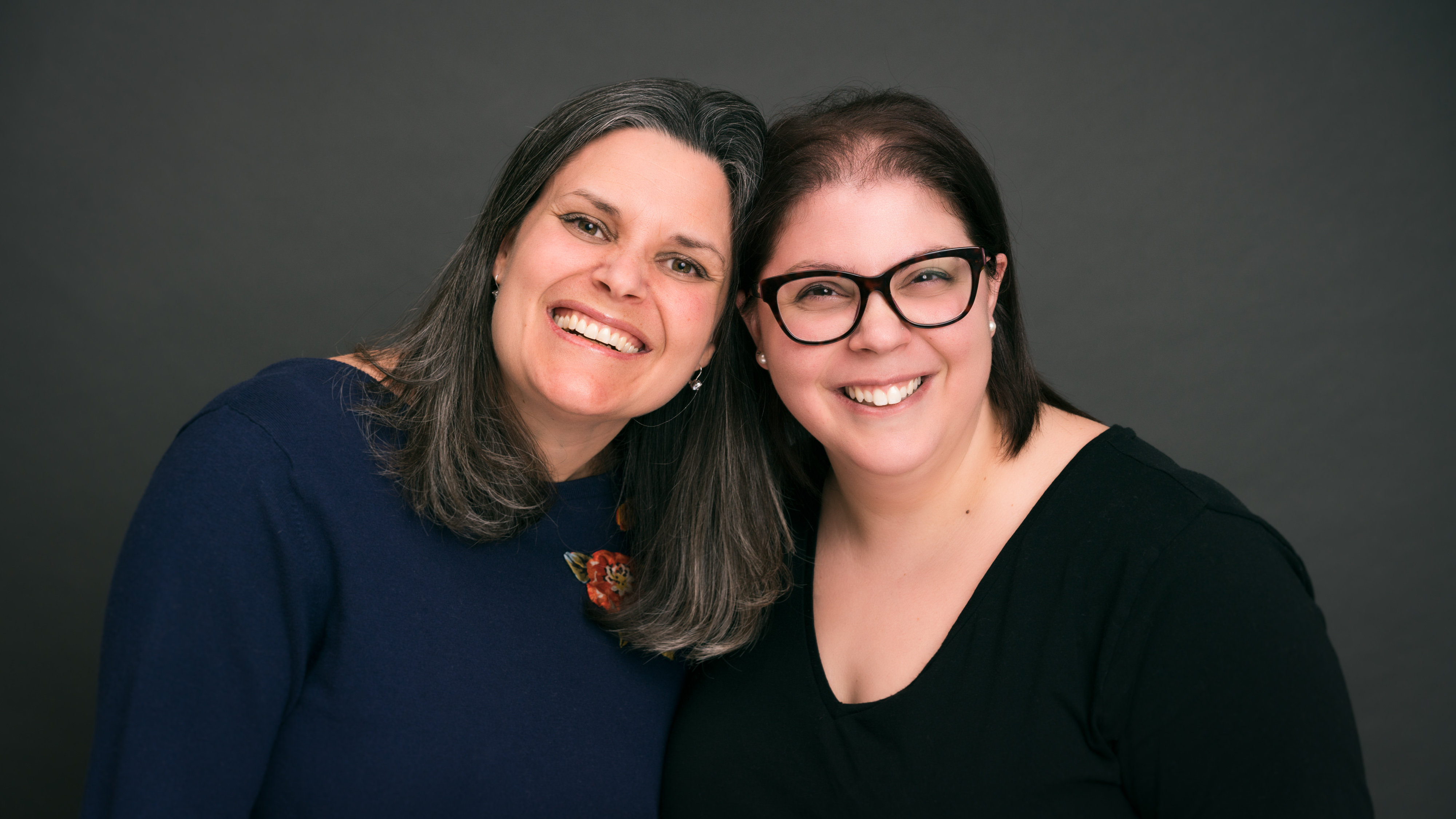 Dr. Martyn and Dr. Merenda pose together, heads touching, in front of a grey background