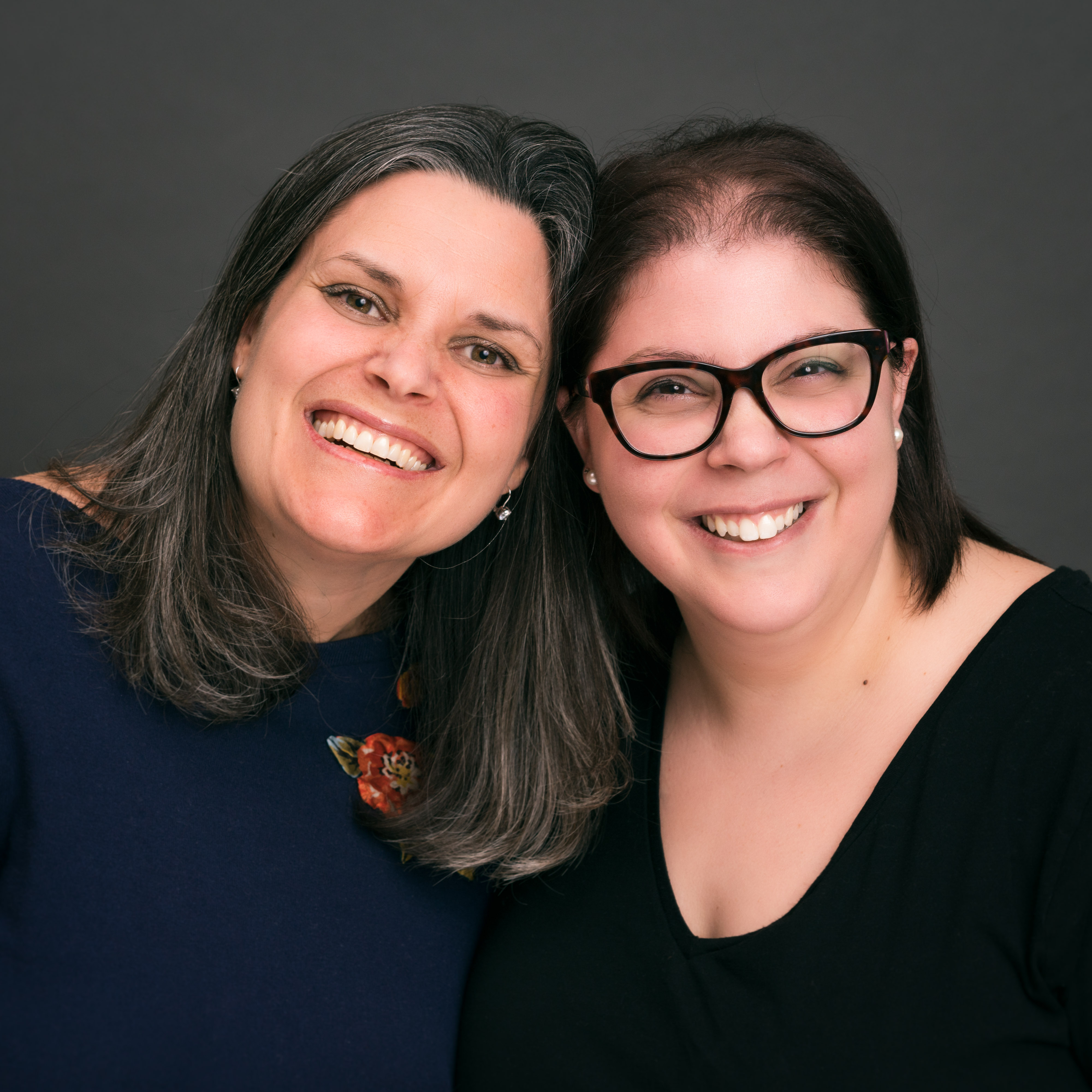 Dr. Martyn and Dr. Merenda pose together, heads touching, in front of a grey background