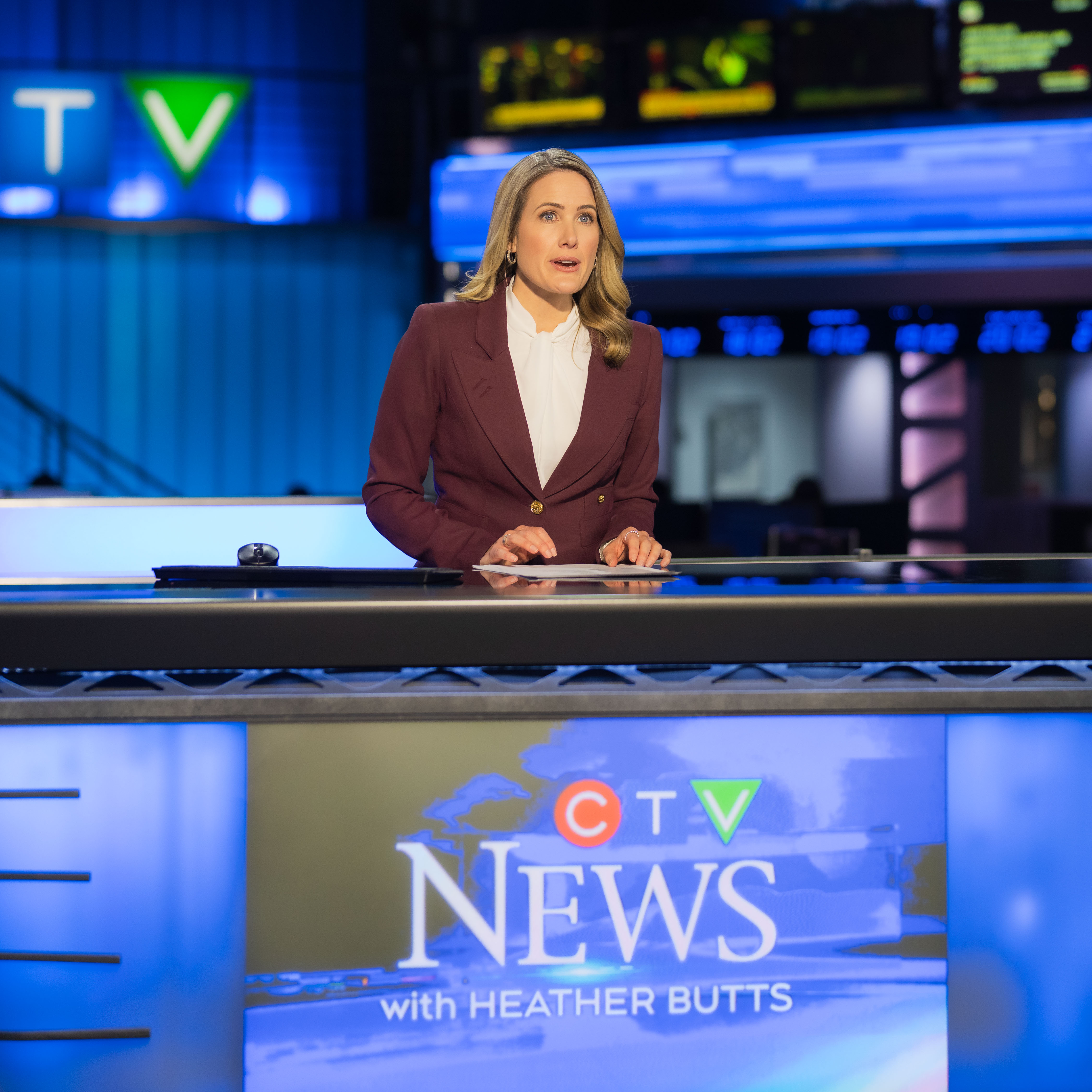 Anchor Heather Butts sits behind the desk reading from a teleprompter in a blue newsroom