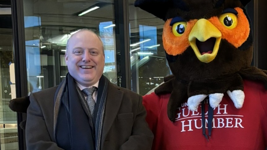 Gary Galbraith poses with Swoop the owl mascot