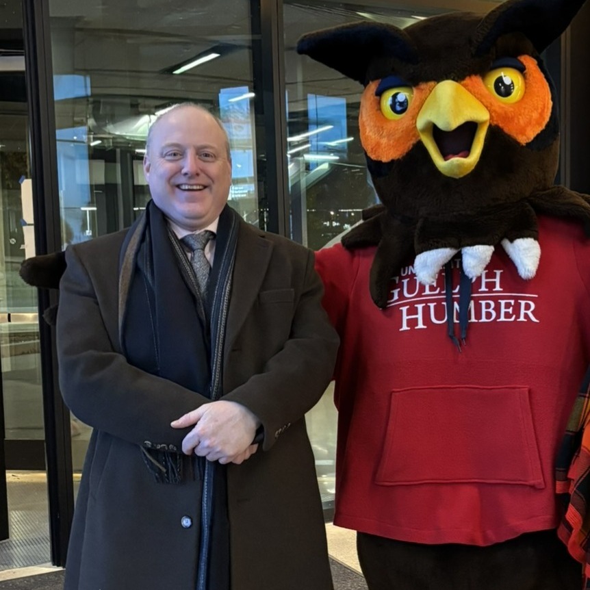 Gary Galbraith poses with Swoop the owl mascot