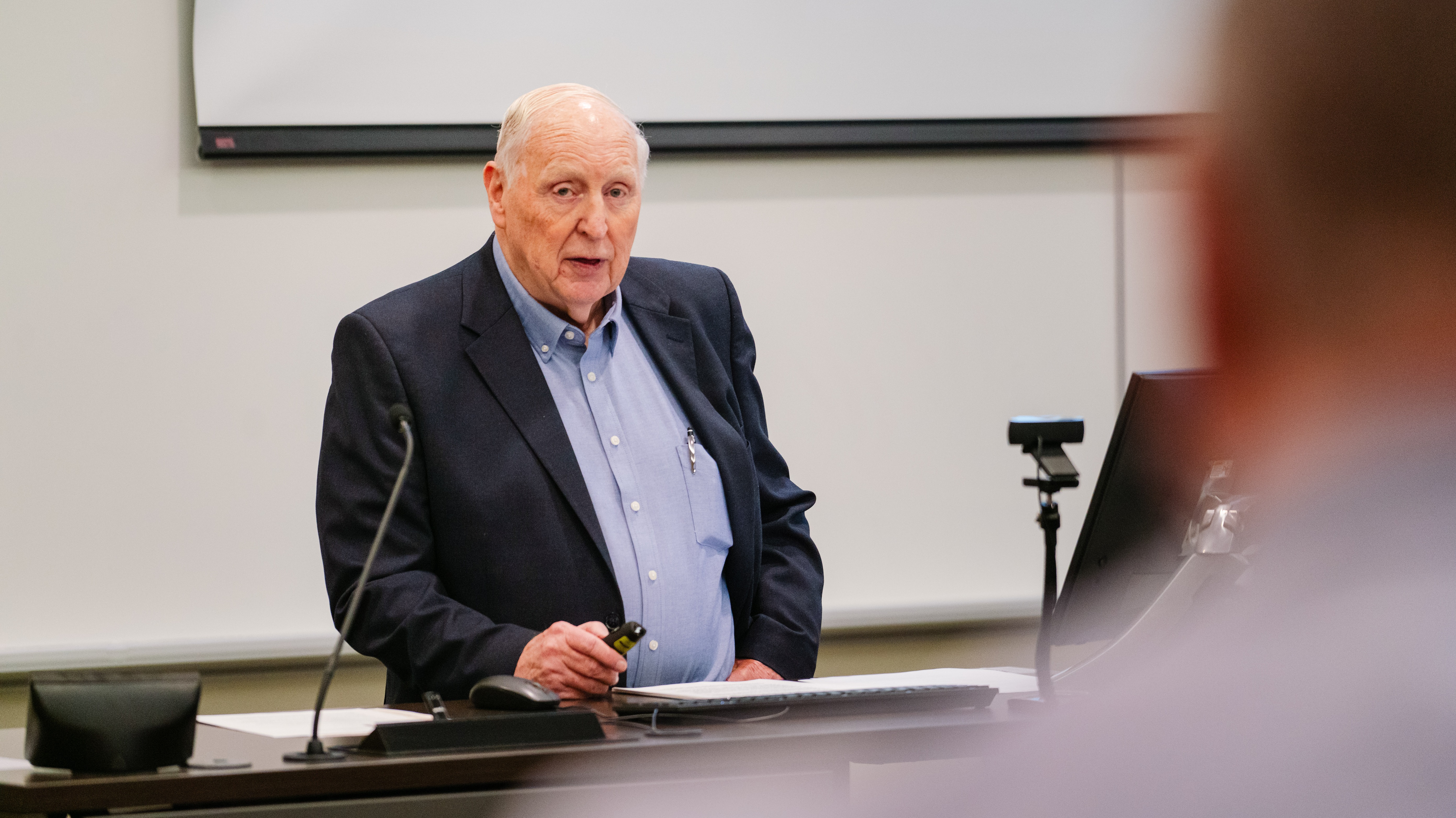 Cal Millar speaks while standing at the front of a lecture hall