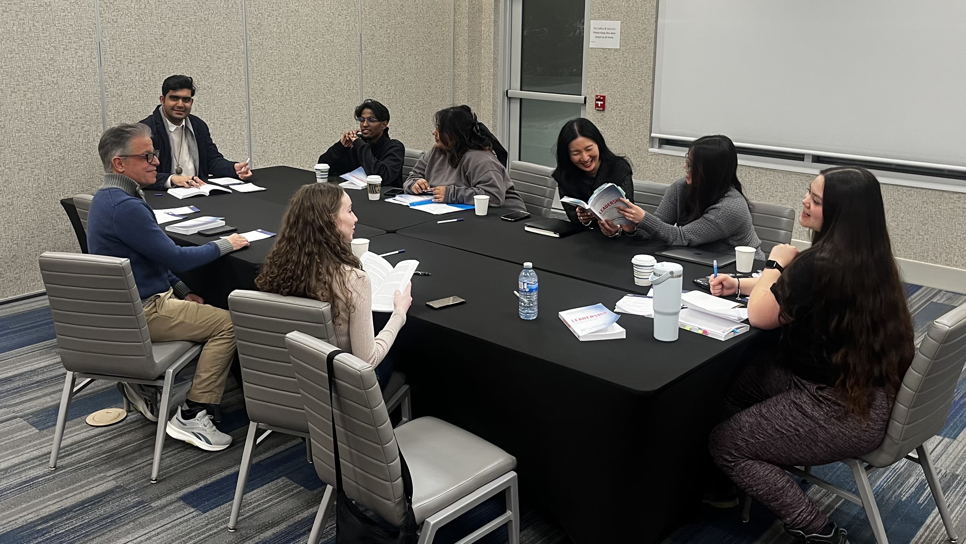 A group of people sit at a table chatting during the Sophia Forum retreat