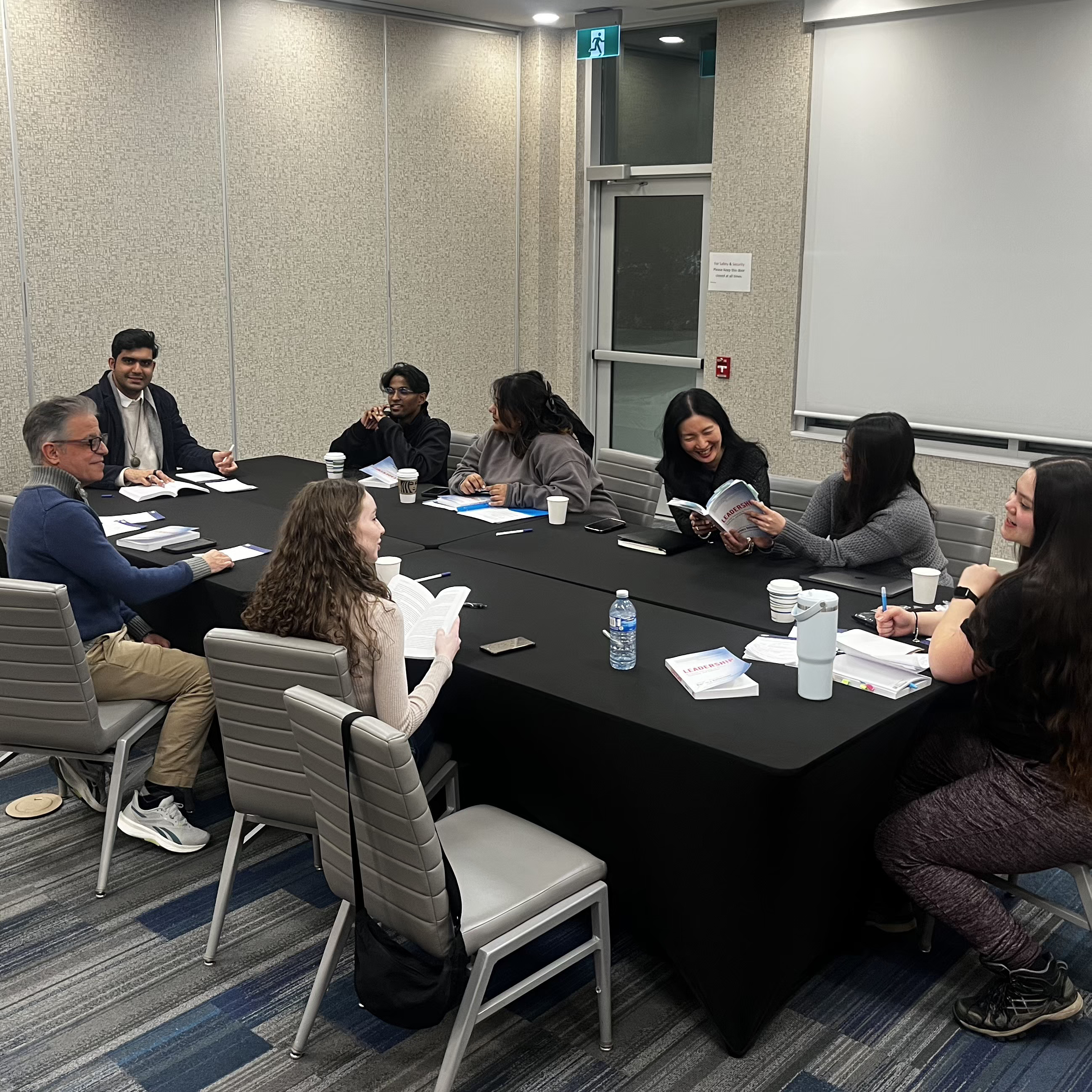 A group of people sit at a table chatting during the Sophia Forum retreat