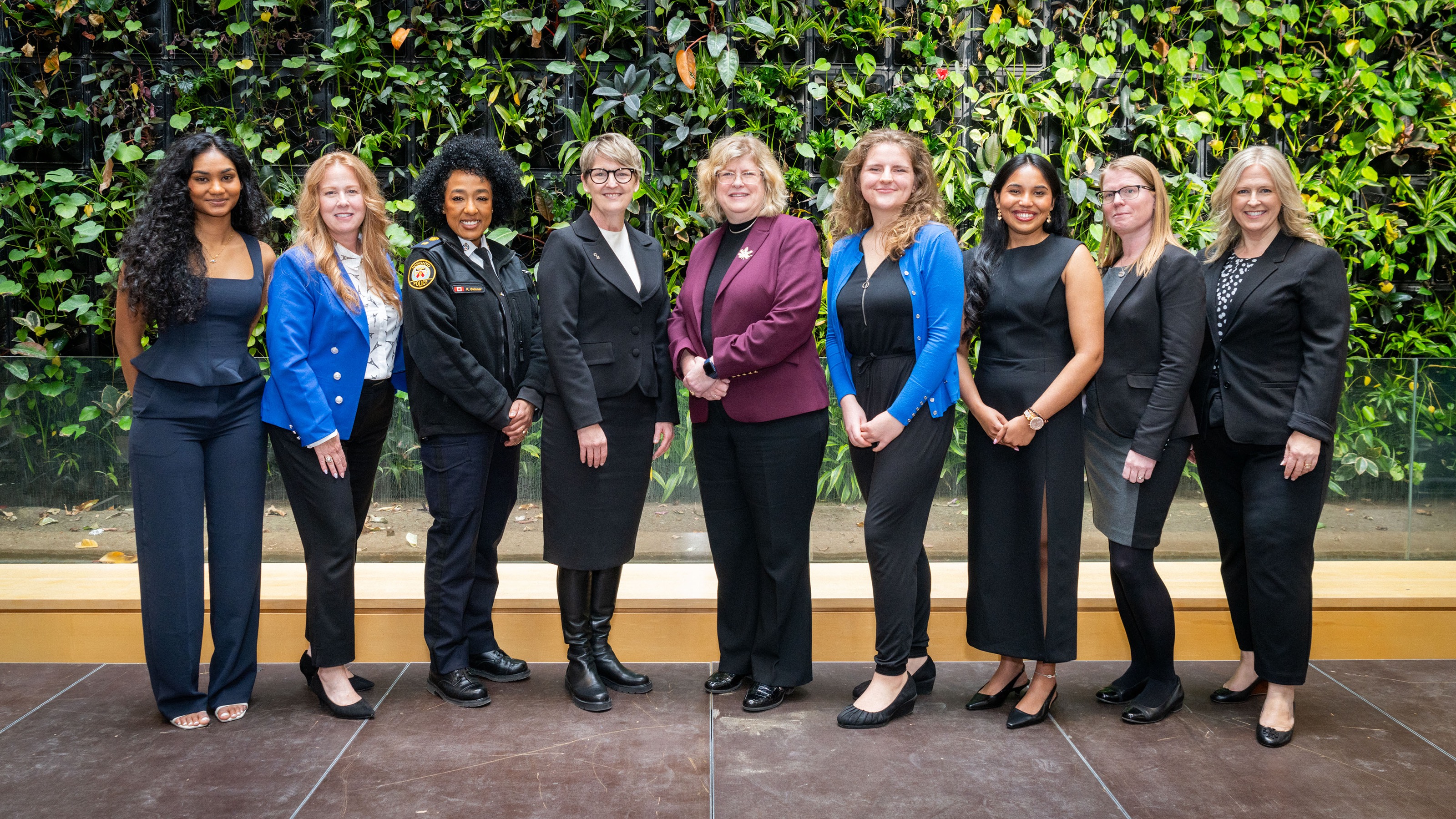 Women of Distinction recipients, moderator Naisha Suthaharan, and Dr. Melanie Spence-Ariemma and Dr. Ann Marie Vaughan stand in front of the living plant wall