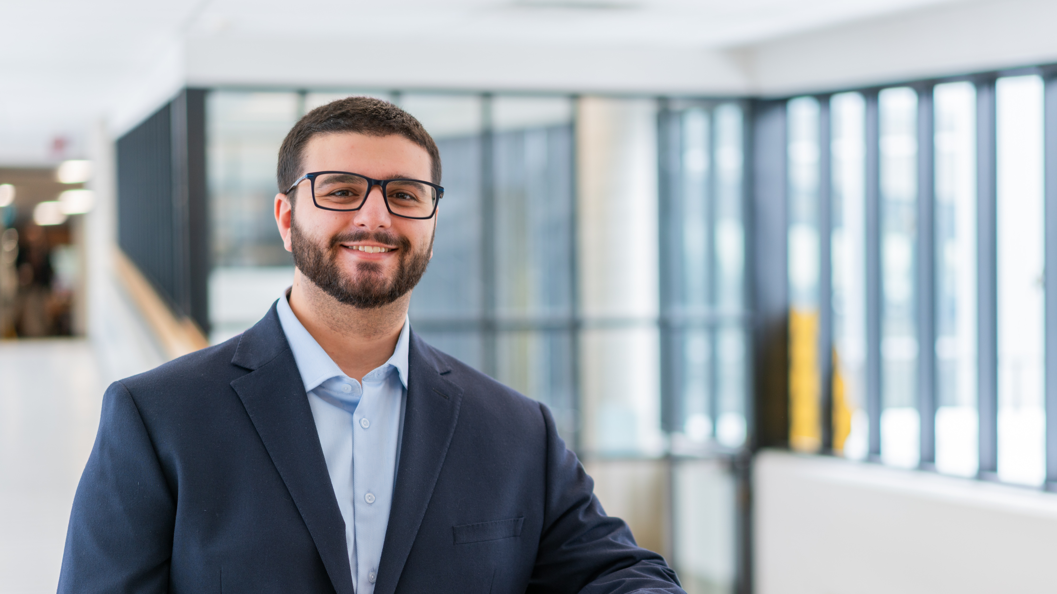 Gino Lucente smiles for the camera wearing a suit and glasses