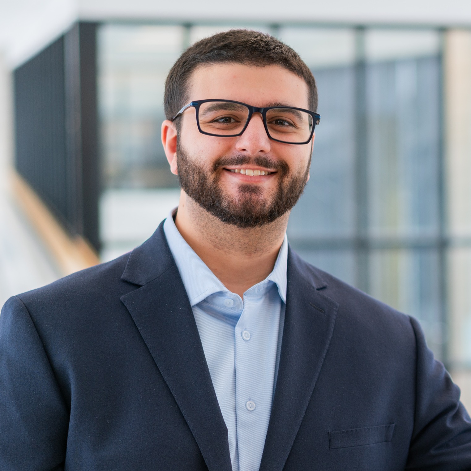 Gino Lucente smiles for the camera wearing a suit and glasses