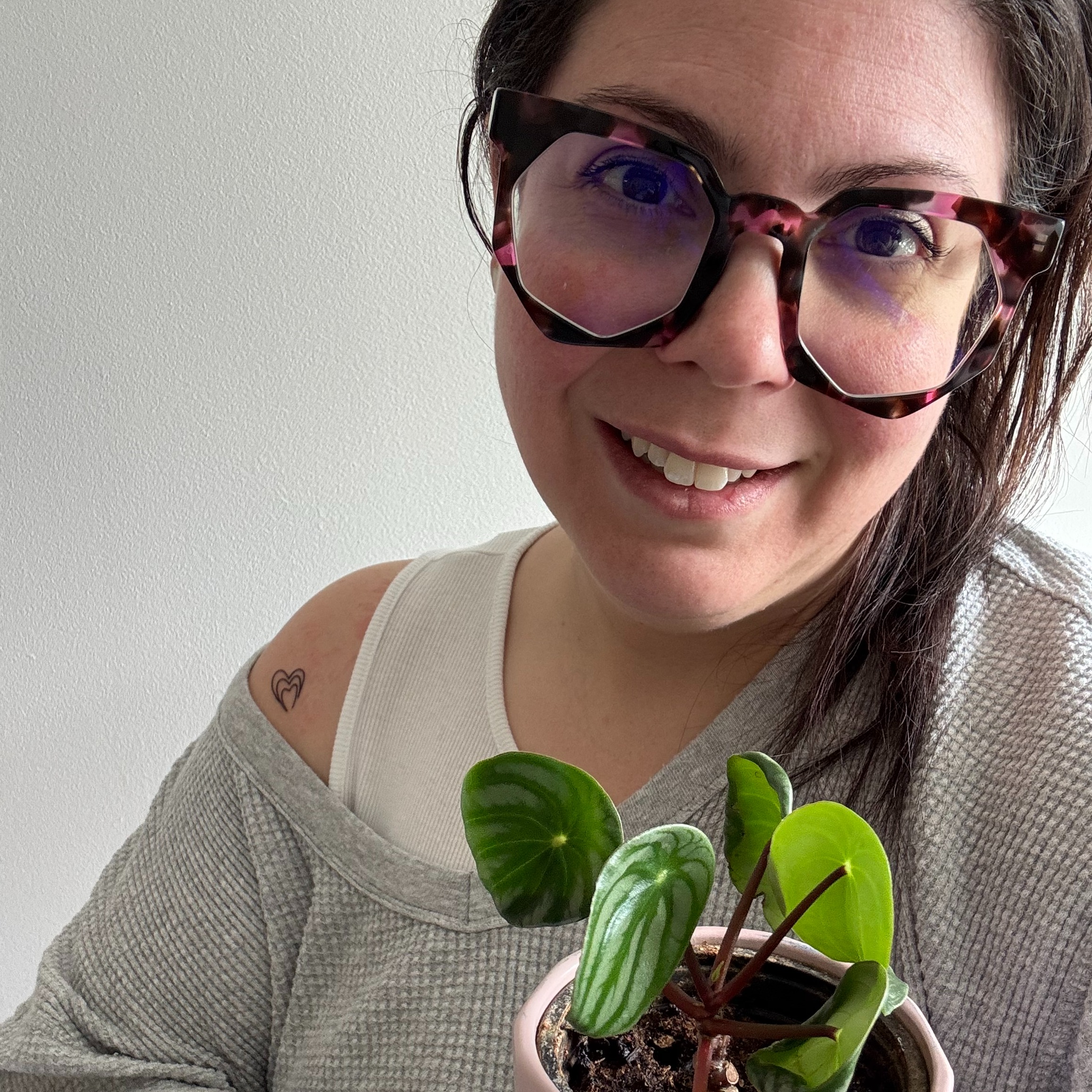Dr. Elena Merenda wears a grey sweatshirt and holds a plant