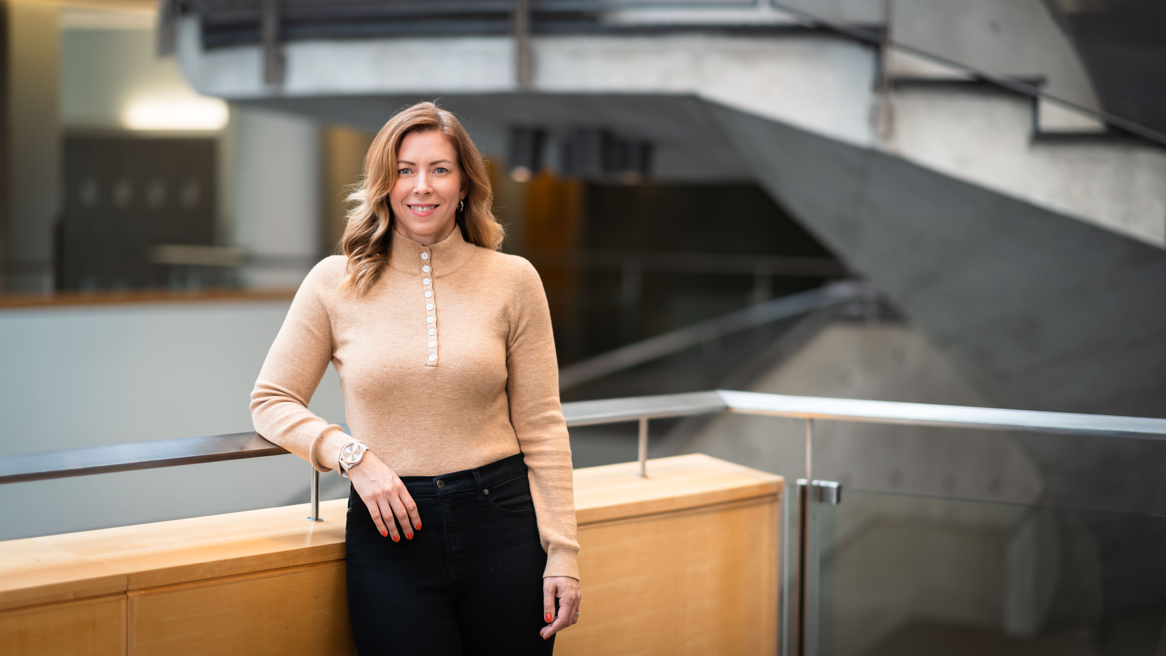 Dr. Allison Reeves stands by a railing with a staircase in the background