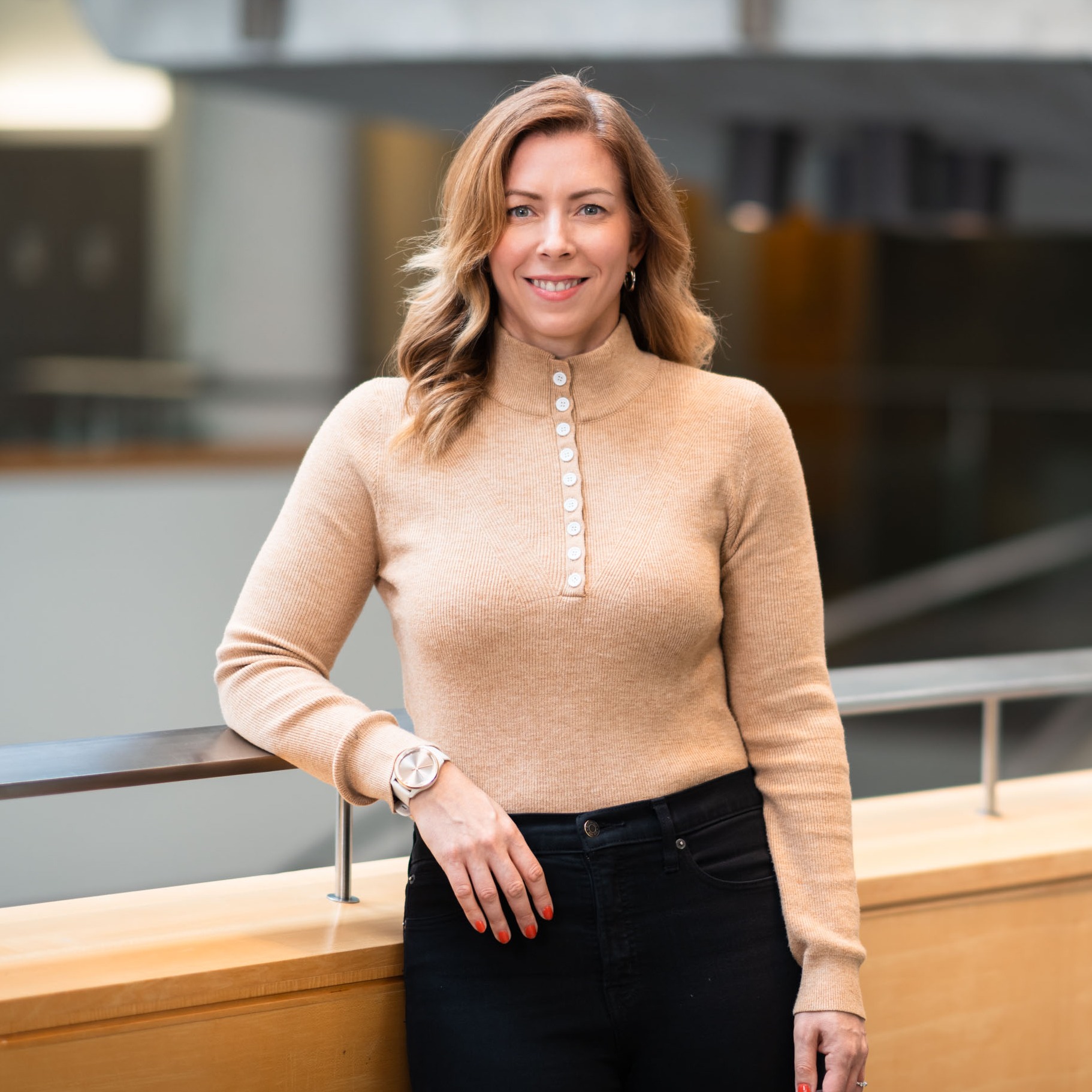Dr. Allison Reeves stands by a railing with a staircase in the background
