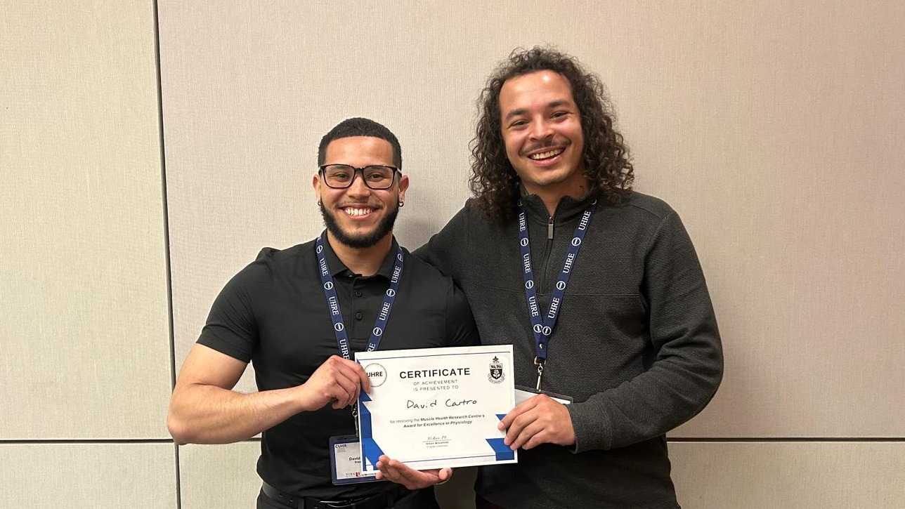 David and Daniel stand together holding David's certificate