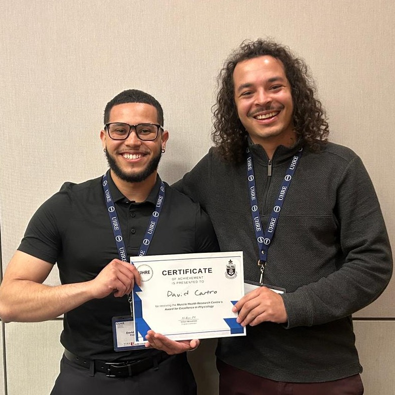 David and Daniel stand together holding David's certificate