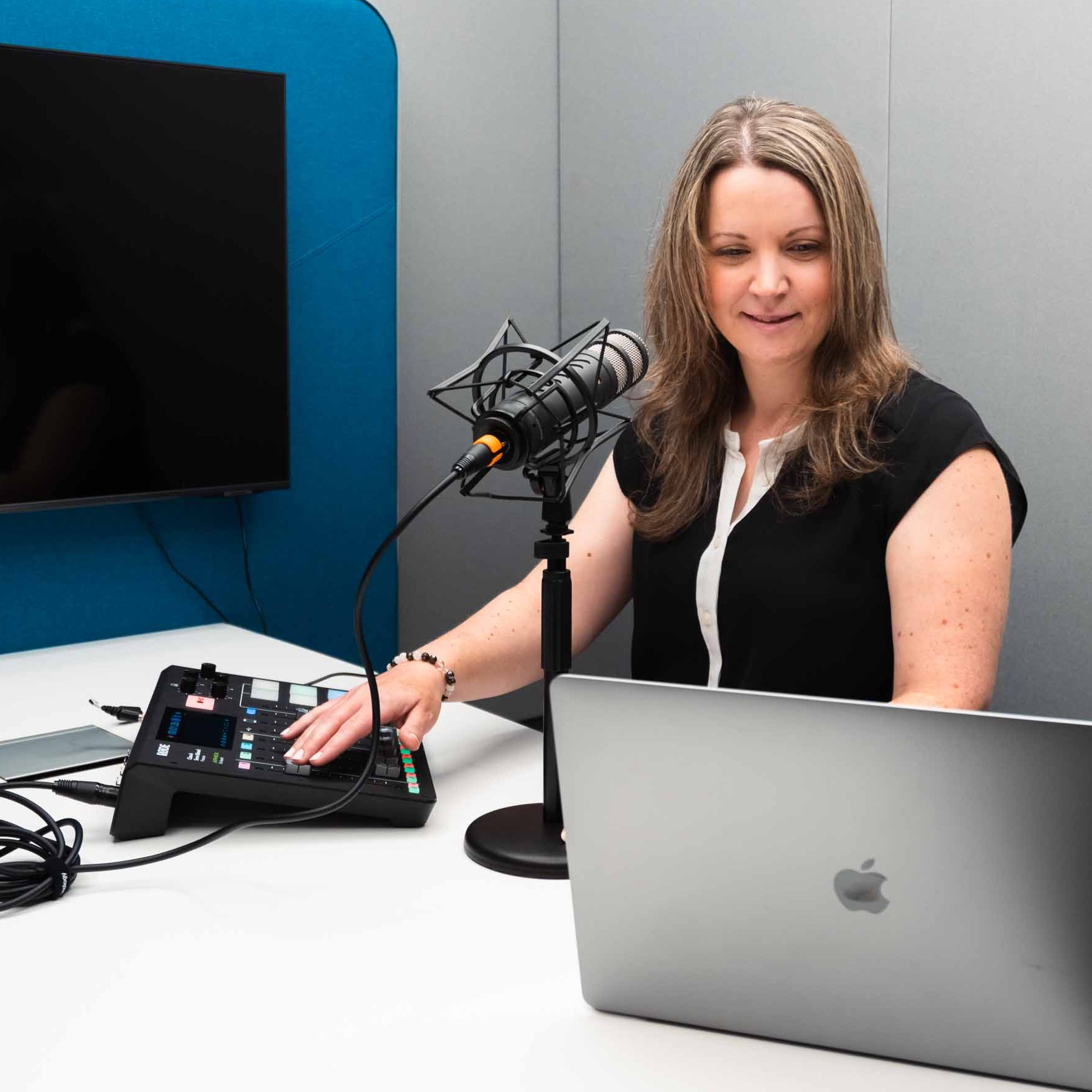 Katie Begley sits in front of a microphone and a laptop as she records her podcast