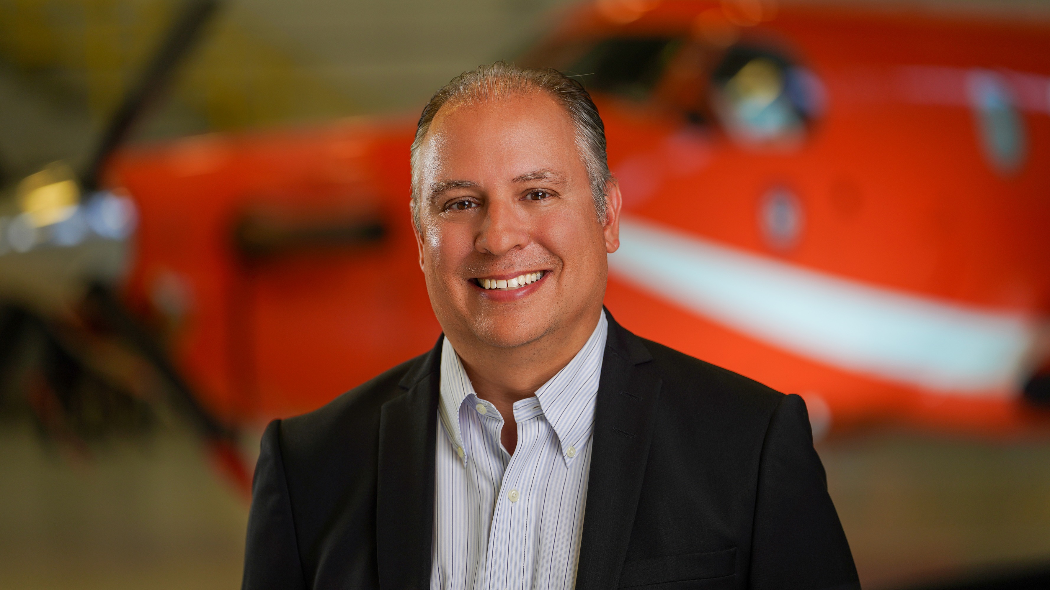 James MacDonald smiles while standing in front of an orange Ornge helicopter