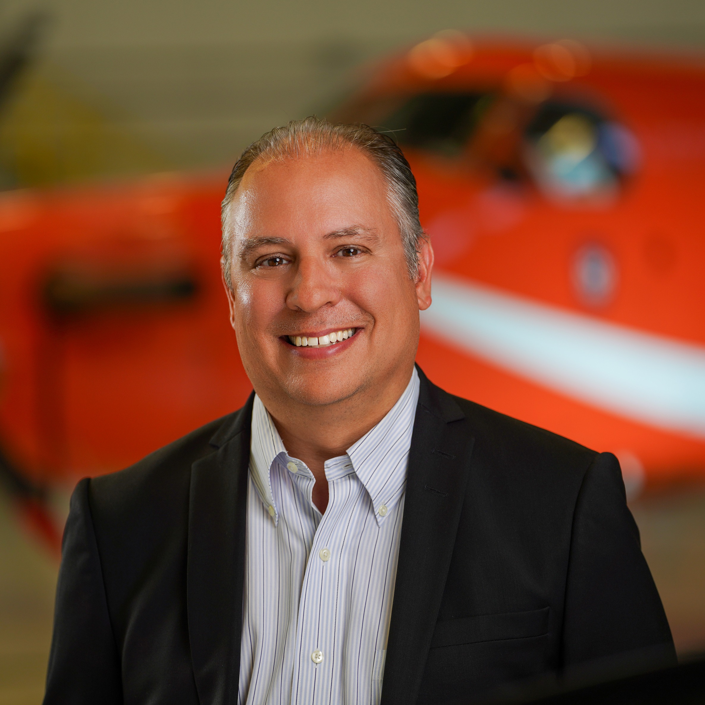 James MacDonald smiles while standing in front of an orange Ornge helicopter