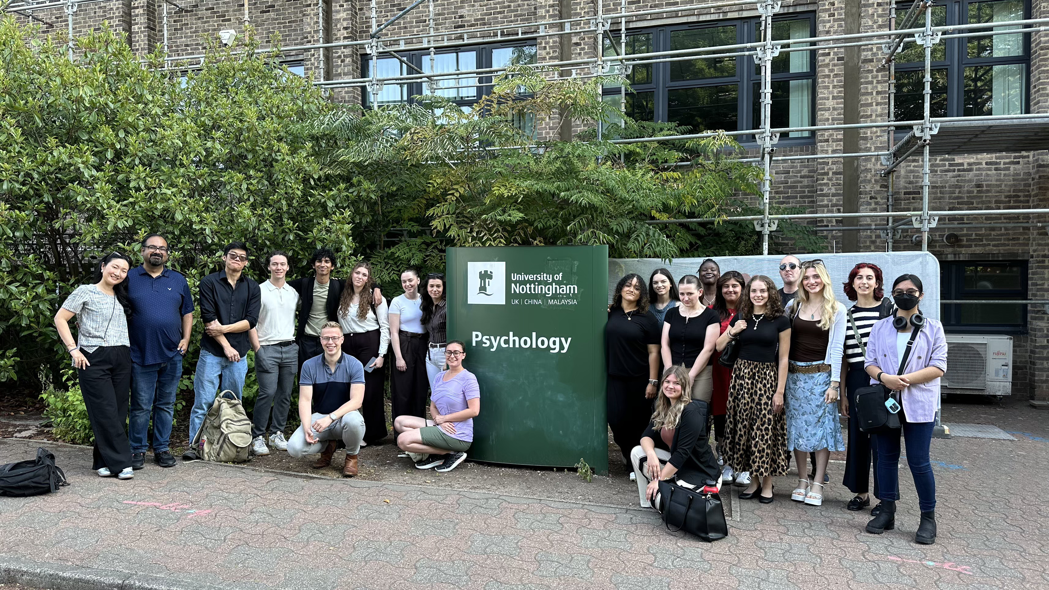 The group poses in front of a University of Nottingham Psychology sign in the U.K.