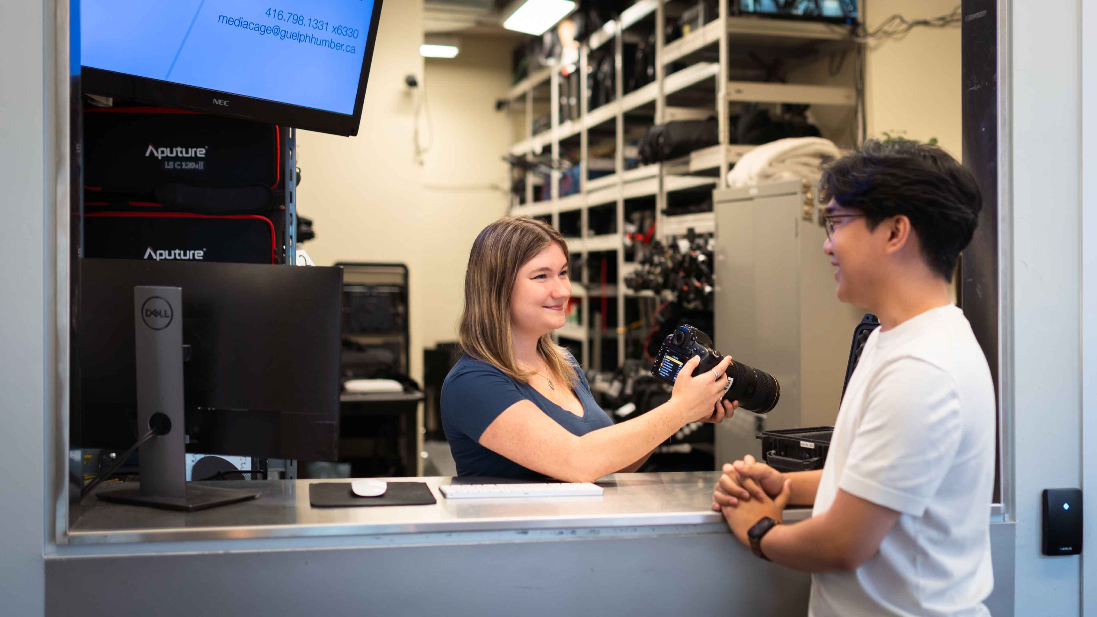 A staff member at the Technology Resource Centre assists a student with a camera