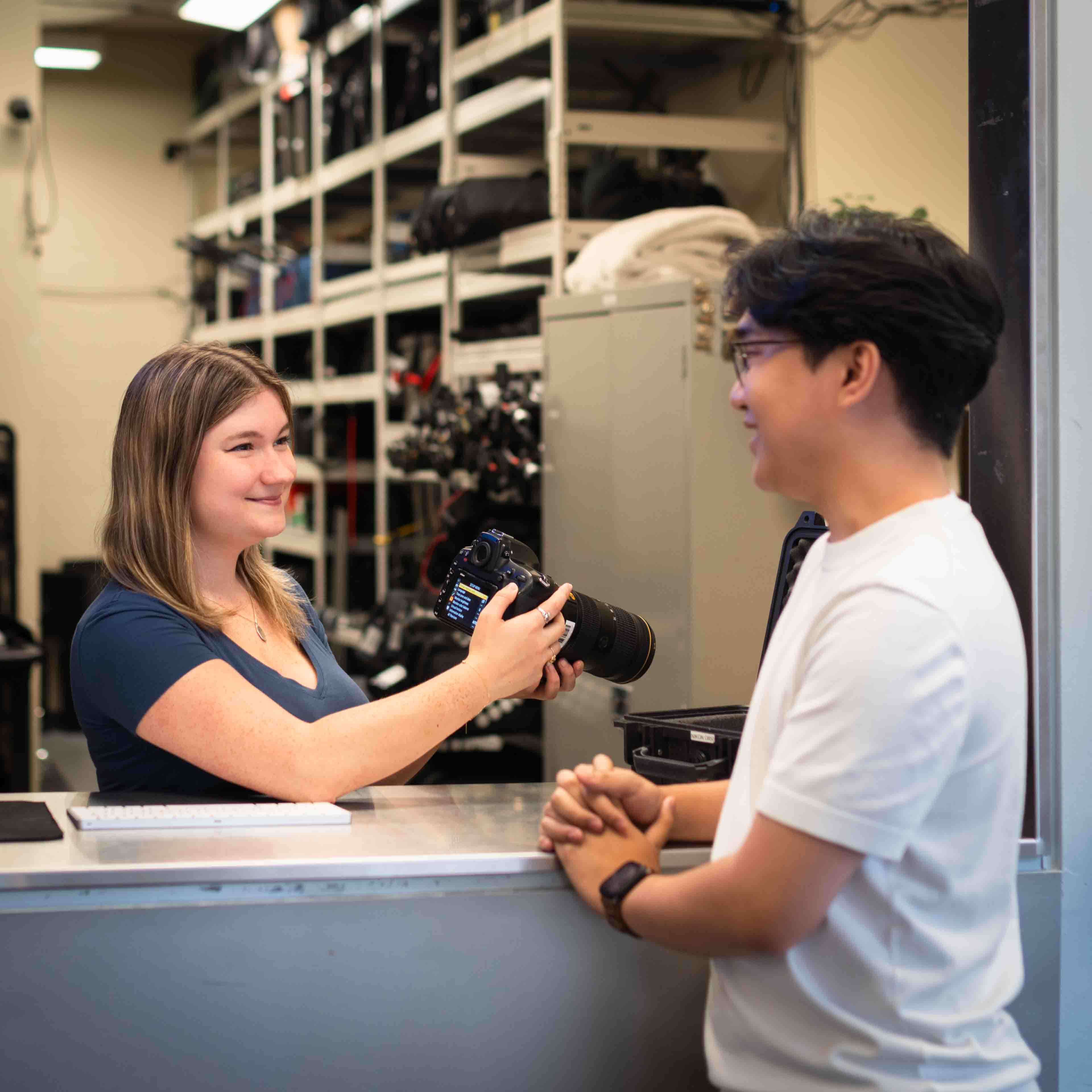 A staff member at the Technology Resource Centre assists a student with a camera