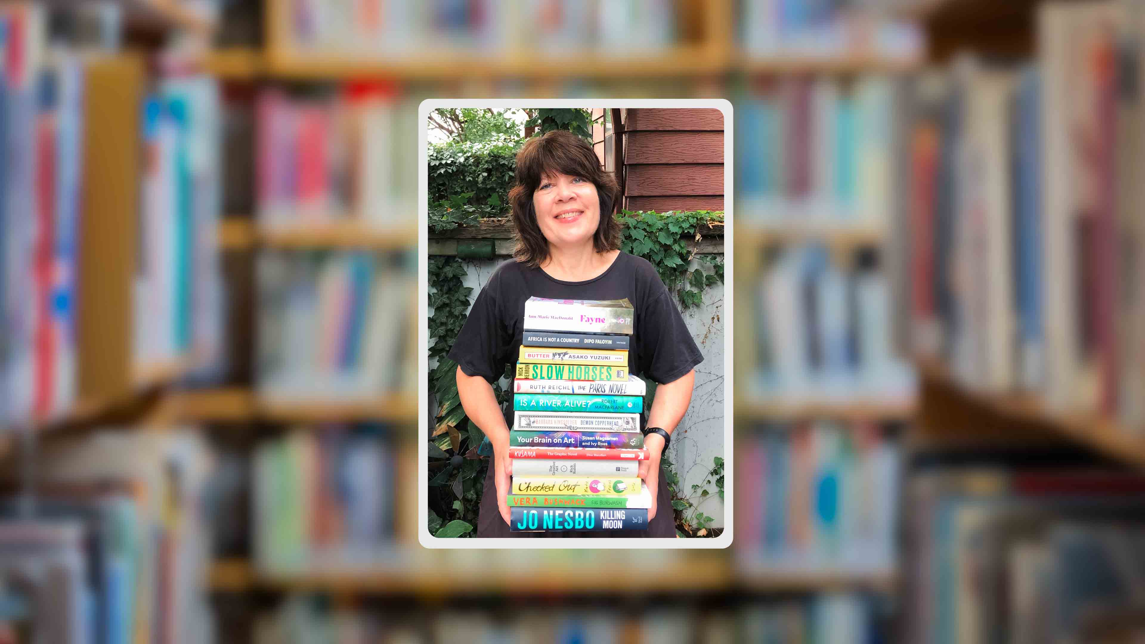 Sue Hunter holds a stack of books, smiling