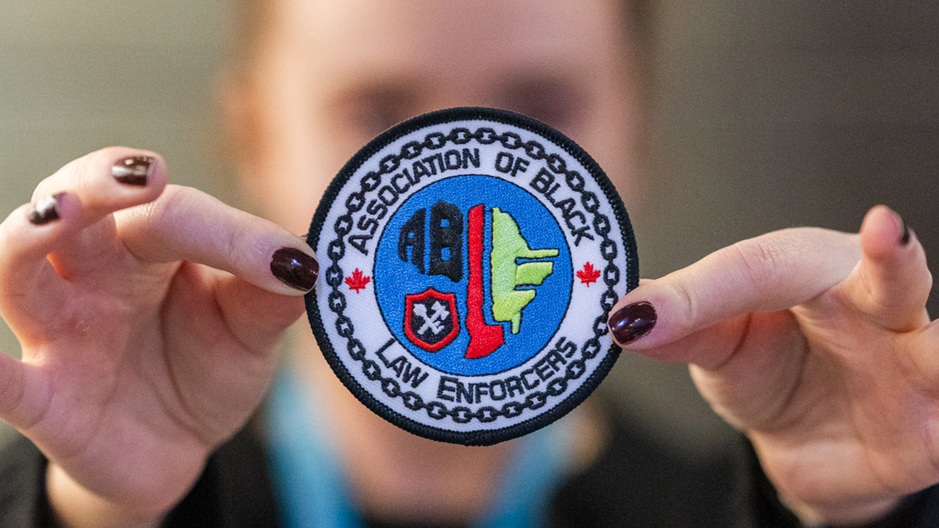 A close up of two hands holding an A.B.L.E. patch